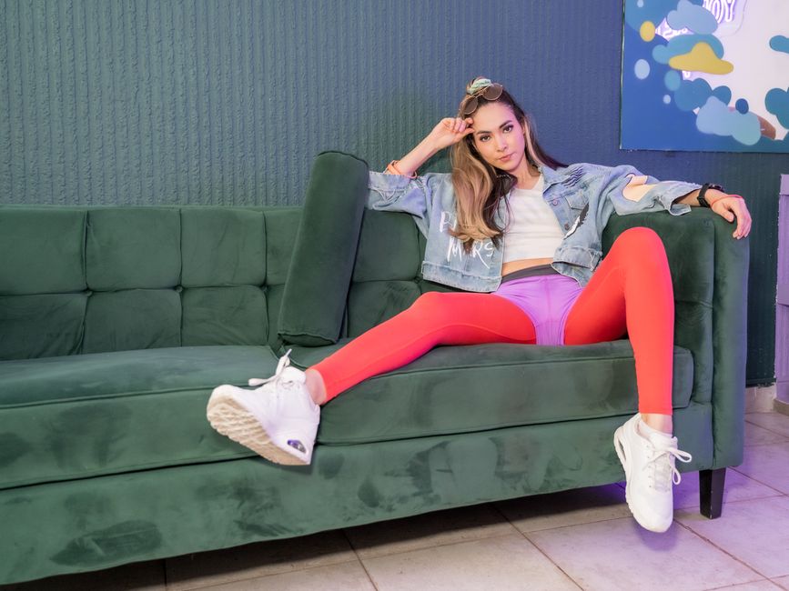 Fashionable woman in trendy outfit reclining on a green sofa indoors, Ciudad de México.