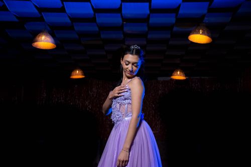 Free An adult woman in a glamorous purple gown posing in a dimly lit setting, exuding elegance. Stock Photo
