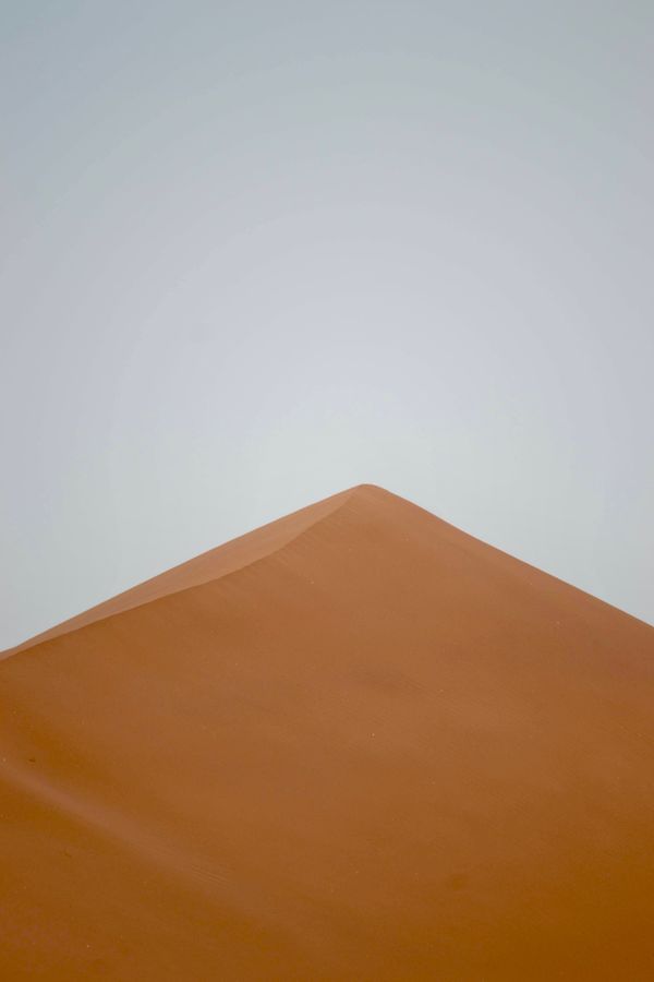 Minimalist sand dune peak in the desert — photo by AbduRahman Ibn Riad on Pexels
