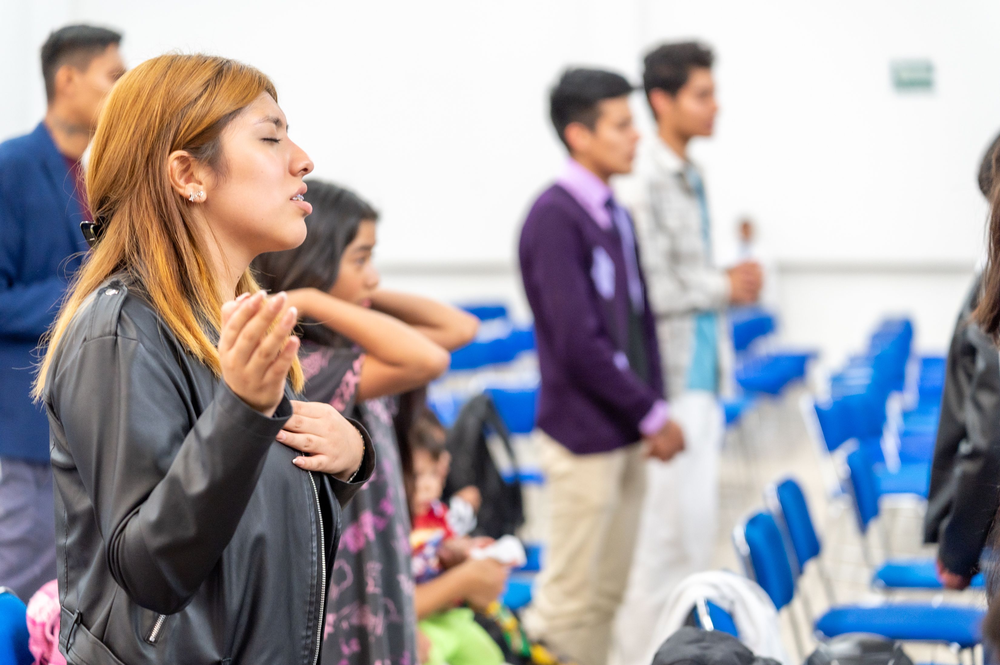 A diverse group of people gathered indoors for a spiritual prayer session in Ciudad de México.