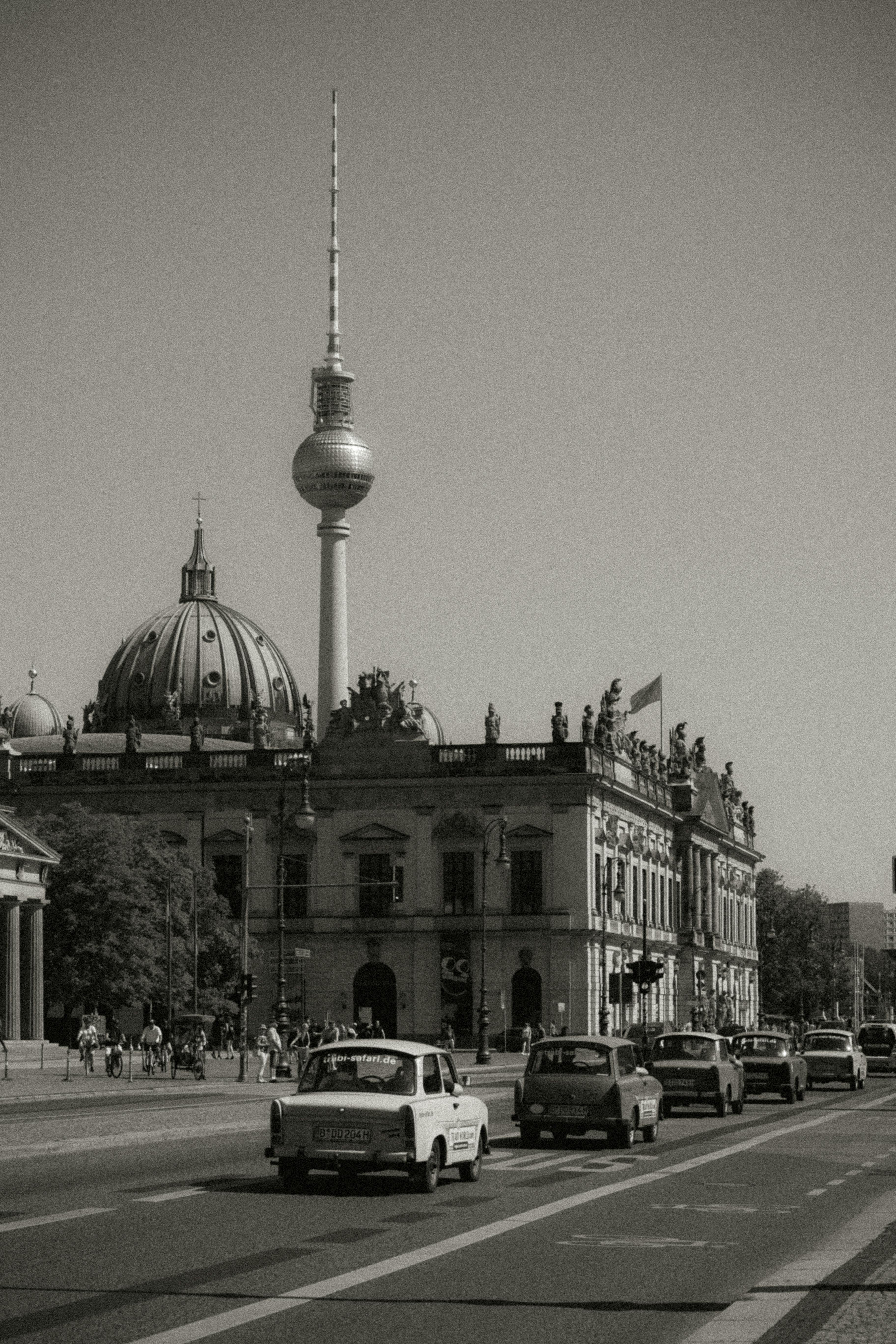 Black and white photo of traffic near Berlin Cathedral and TV Tower.