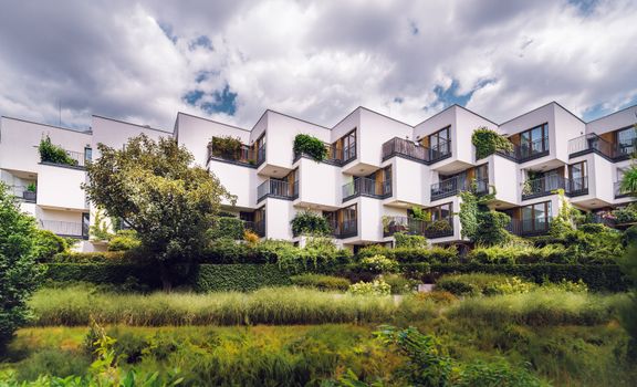 Contemporary apartment complex featuring sustainable architecture with lush greenery and open balconies.