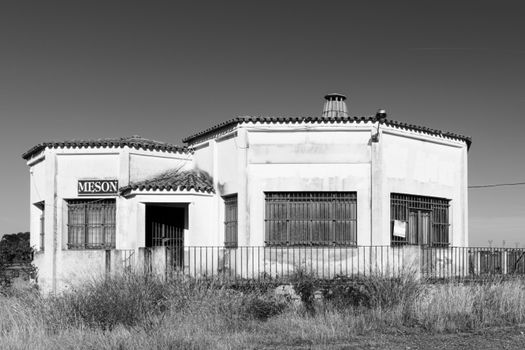 Grayscale image of an abandoned building with a 'Meson' sign, emphasizing urban decay.