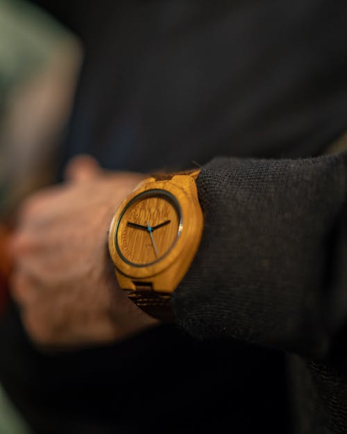 둥근 갈색 아날로그 시계를 착용 한 사람의 선택적 초점 사진