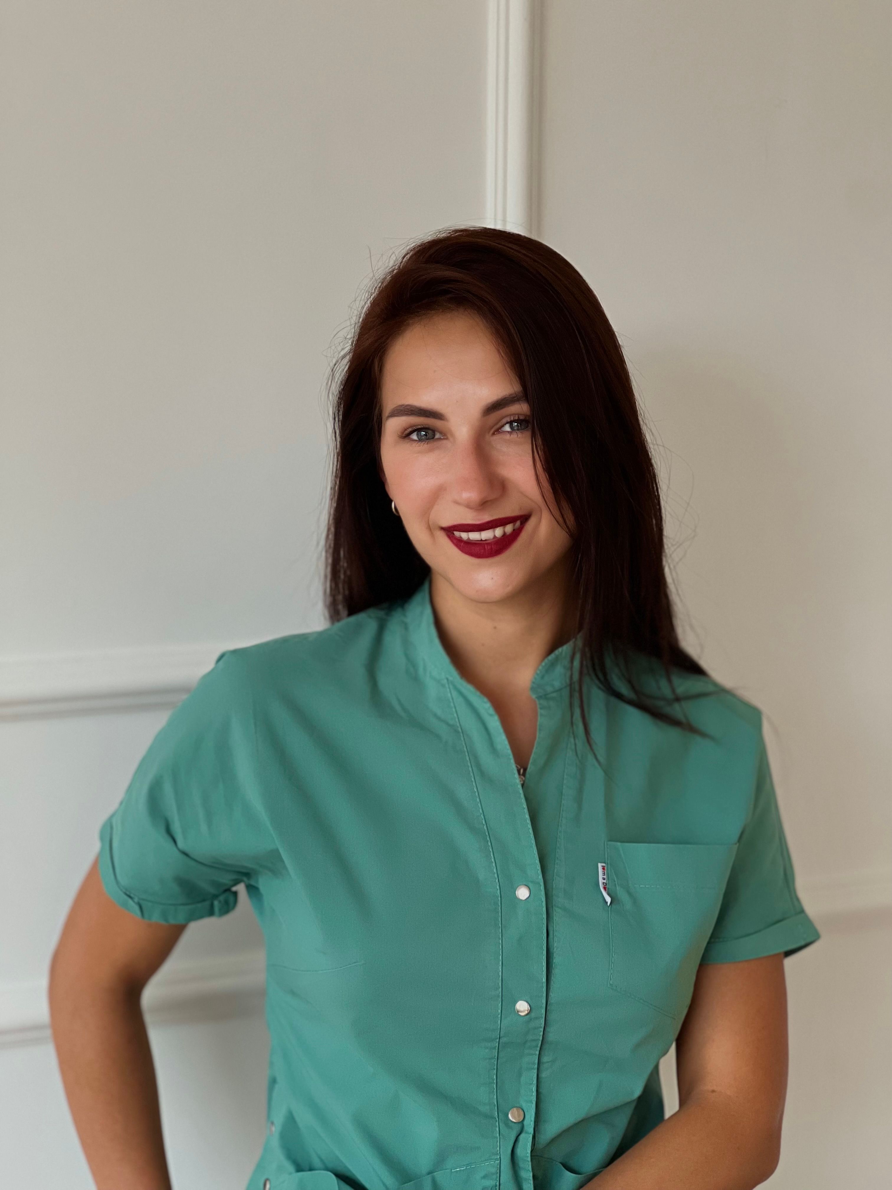Portrait of a young adult woman with long brunette hair, smiling indoors.