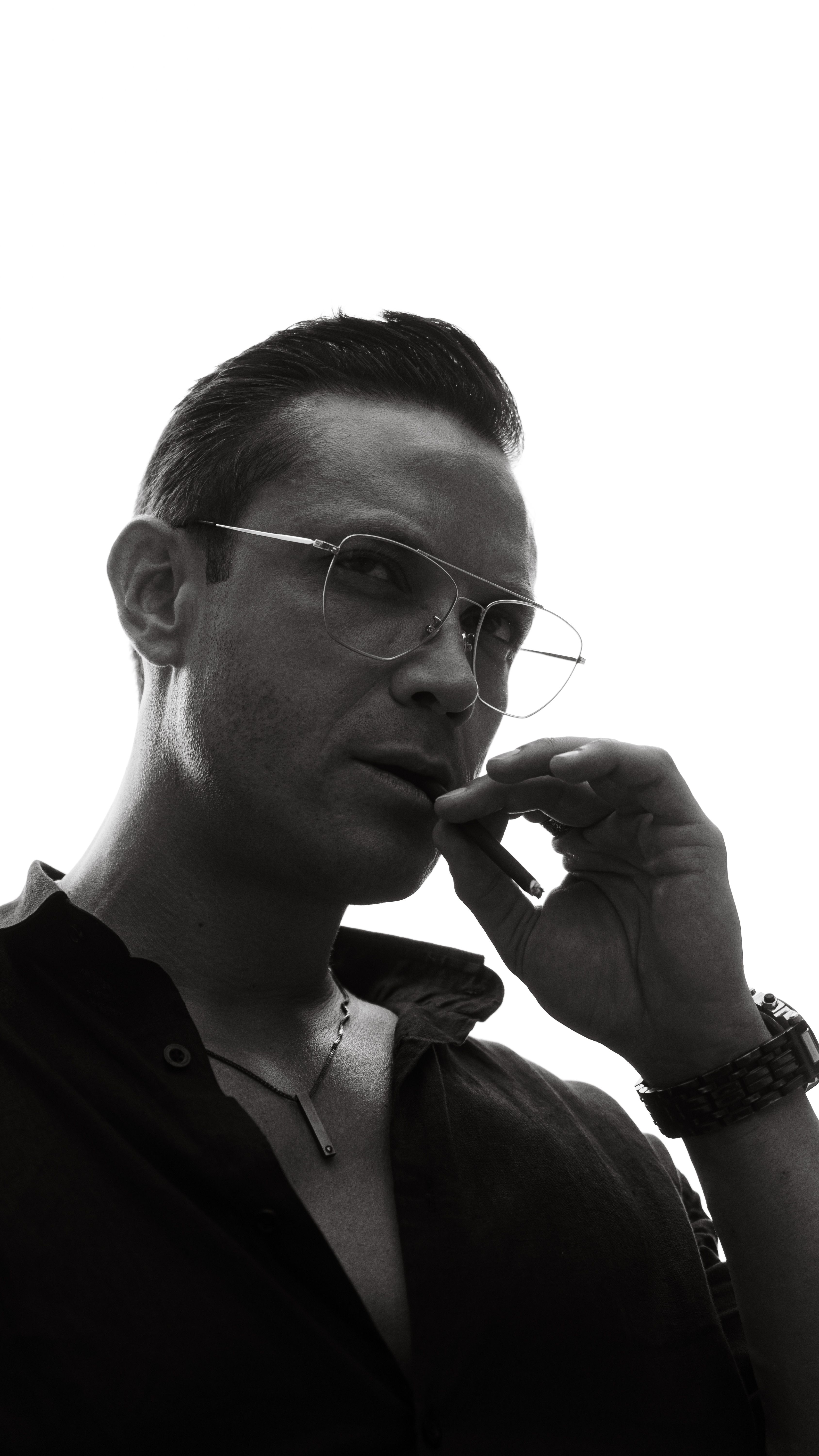 Black and white portrait of a man with eyeglasses in a thoughtful pose, exuding style and elegance.
