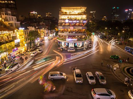 A bustling Hanoi intersection captured at night with vibrant lights and busy traffic.