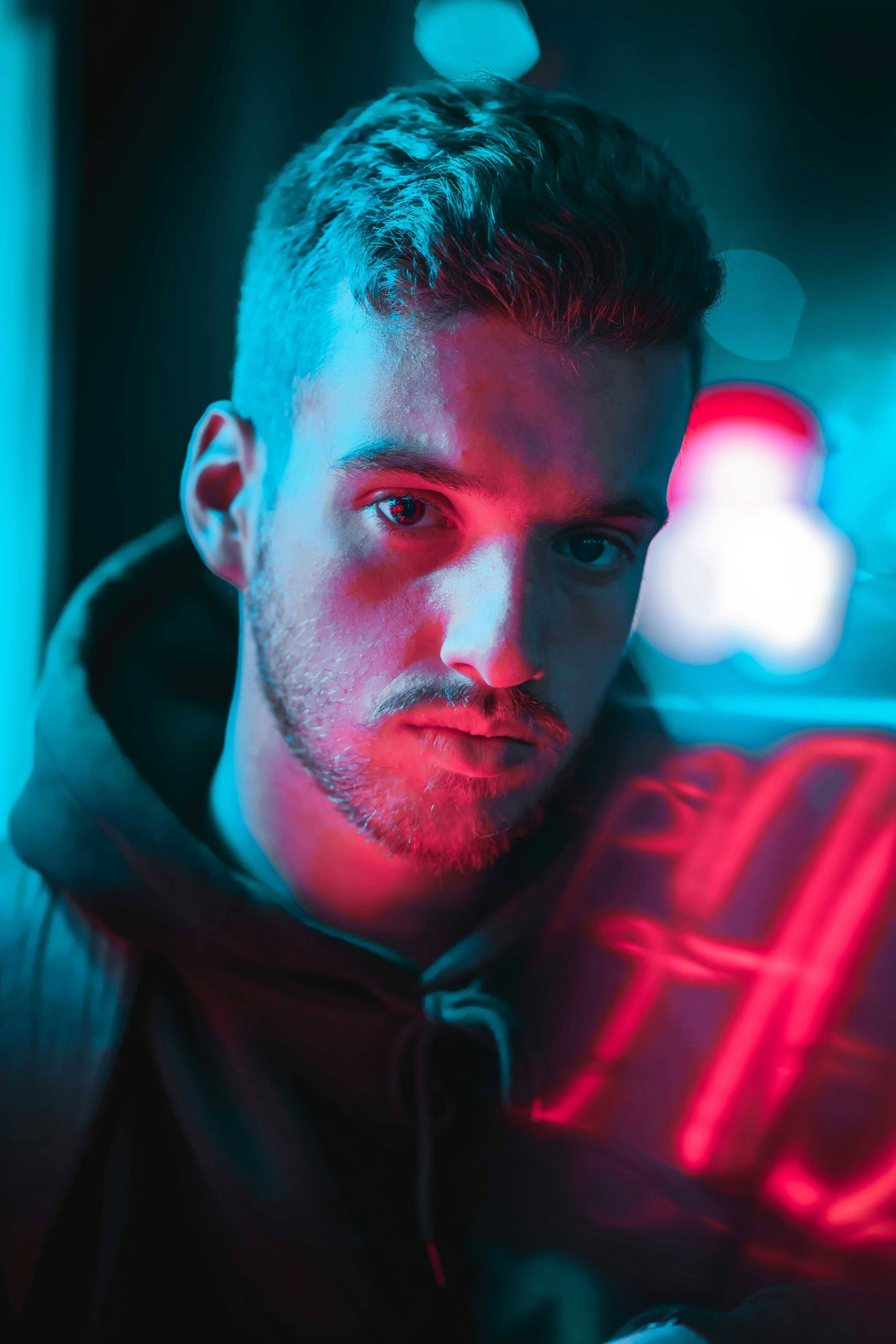 渥太华夜色中，一名身穿连帽衫的男子在霓虹灯下的特写镜头