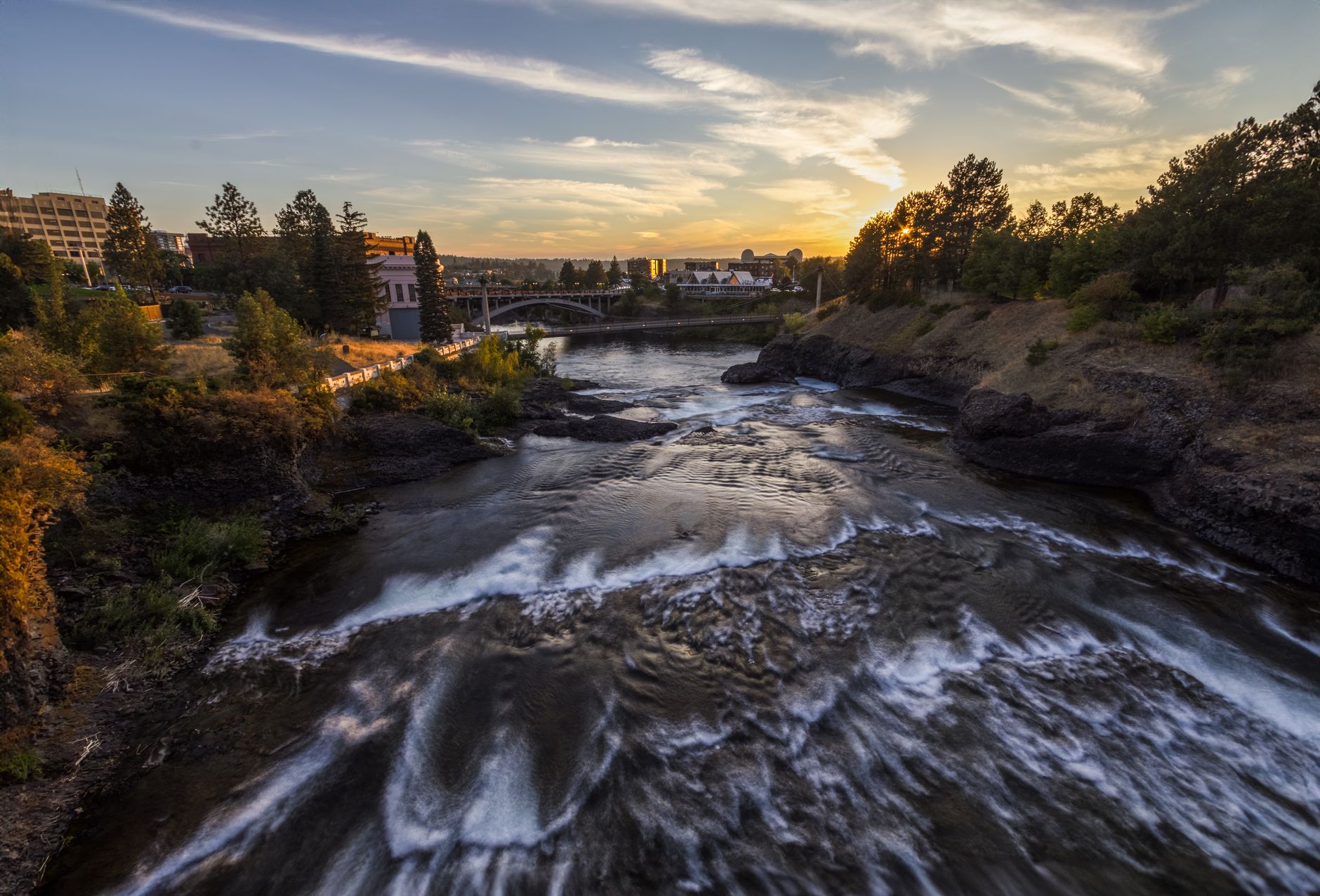 Beautiful view of Spokane River flowing through the city at sunset, capturing the tranquil essence of nature and urban landscape.