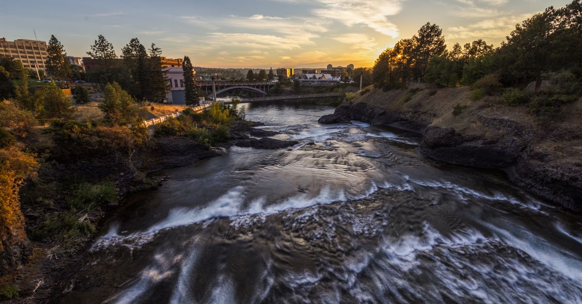 Beautiful view of Spokane River flowing through the city at sunset, capturing the tranquil essence of nature and urban landscape.