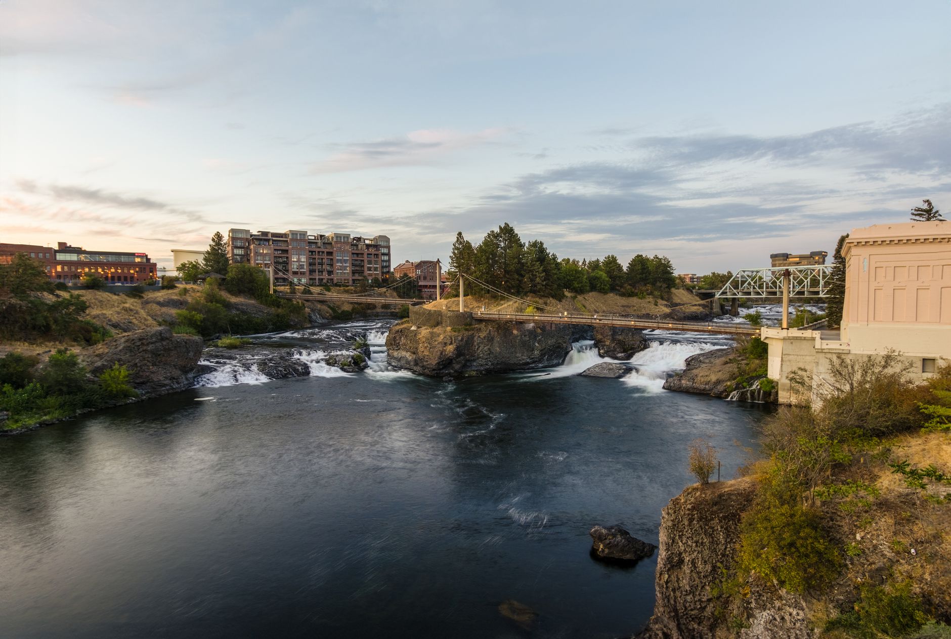 A beautiful view of the Spokane Falls with a bridge and urban landscape, captured at sunset.