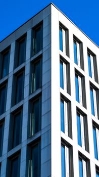 Angle view of a contemporary office building facade against a clear blue sky.