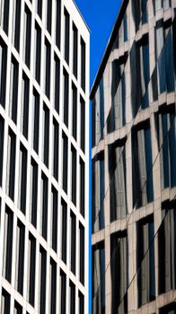 Close-up of two modern office buildings with glass windows against a blue sky.