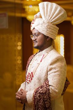 Portrait of a groom in traditional Bangladeshi attire at a wedding ceremony indoors.