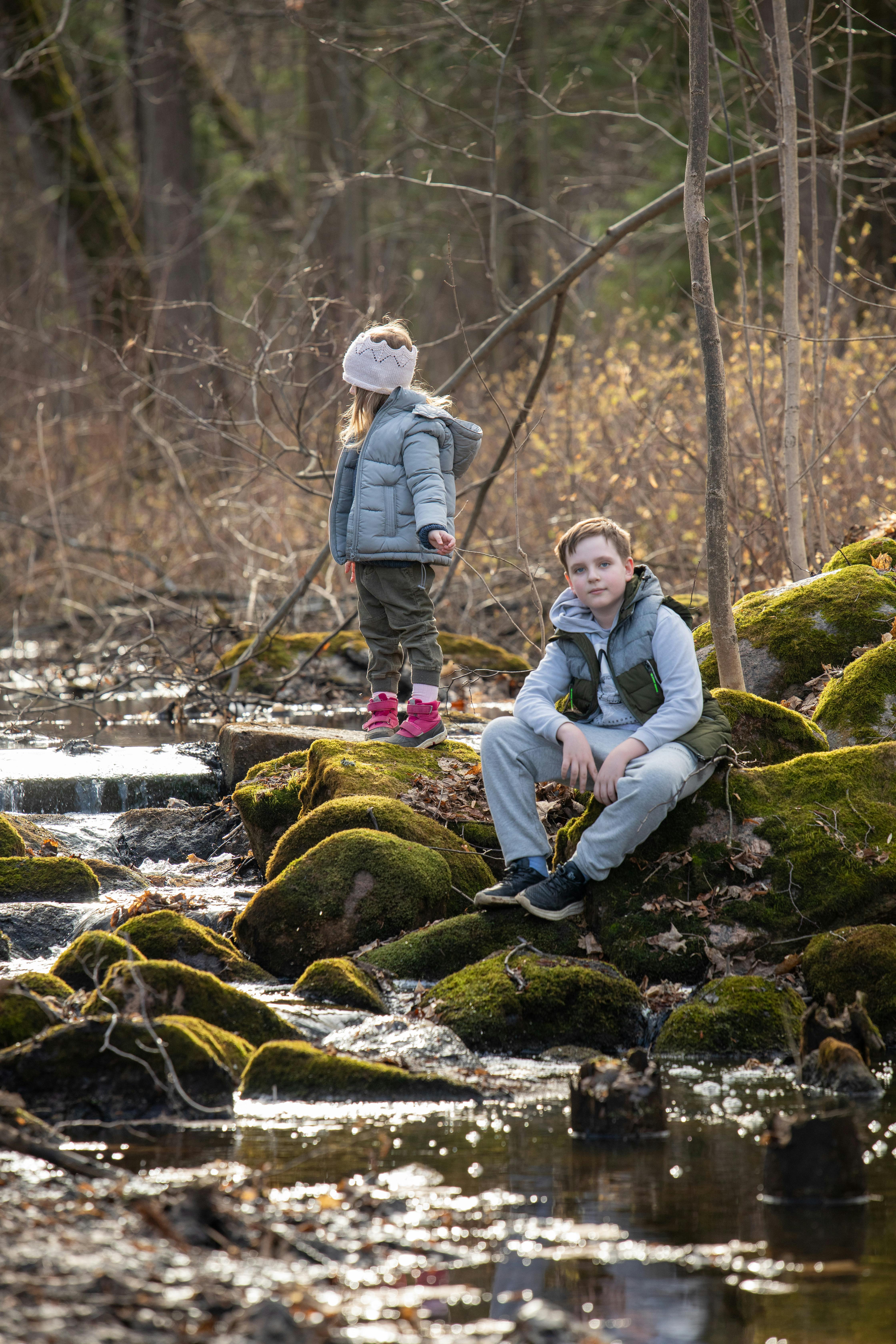 a man and a child sitting on rocks in a stream