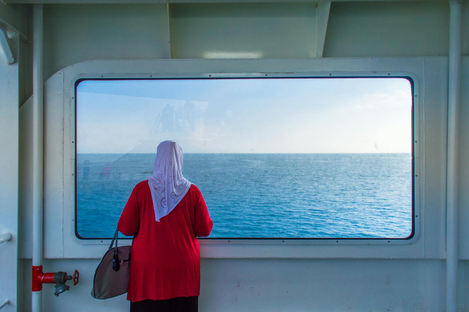 Woman Travelling on a Cruise Ship Looking out the Window at the View of the Sea