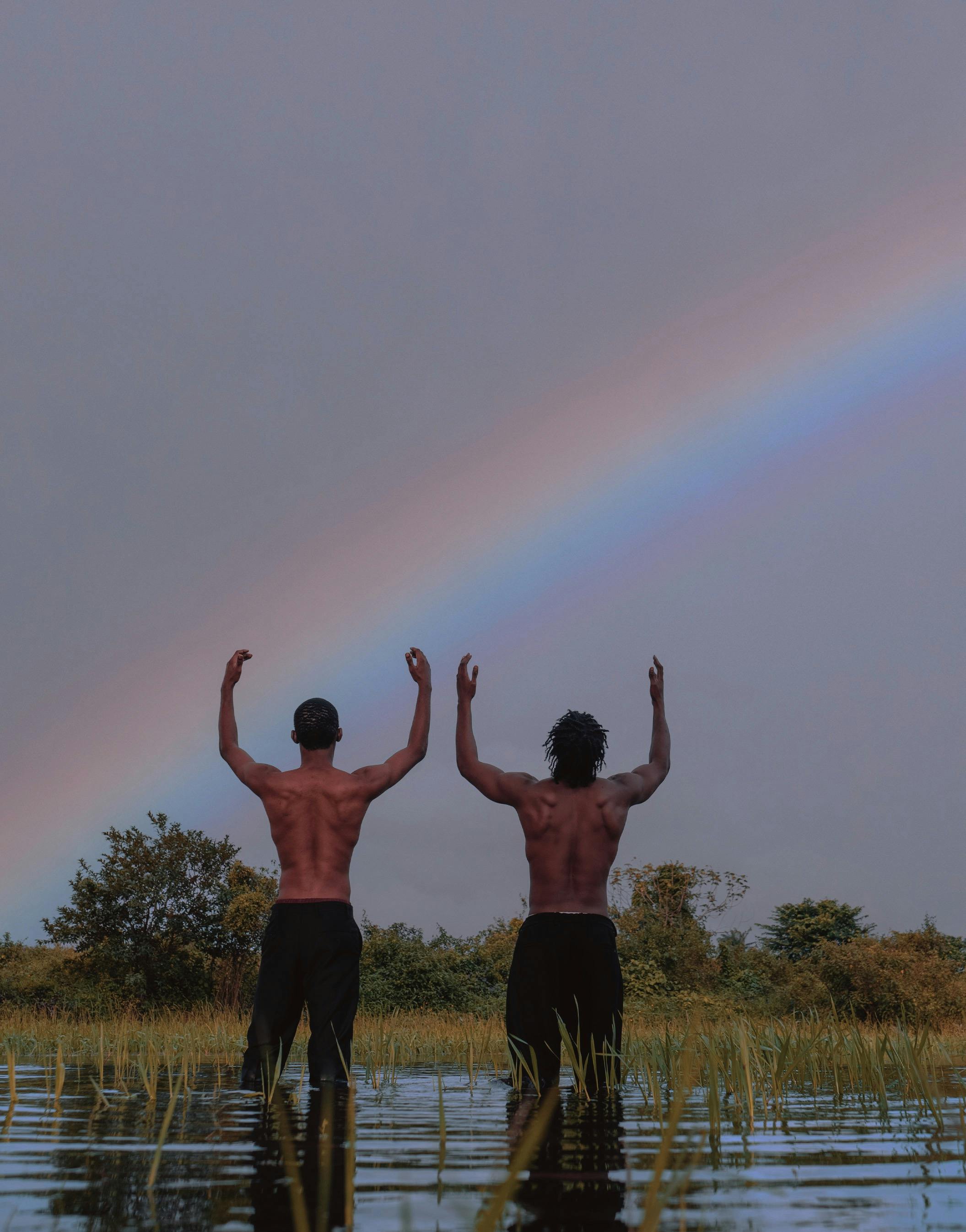 two men standing in the water with their arms up in the air