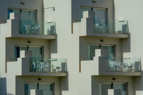 Free Architectural view of modern apartment balconies with sleek glass railings and outdoor furniture. Stock Photo