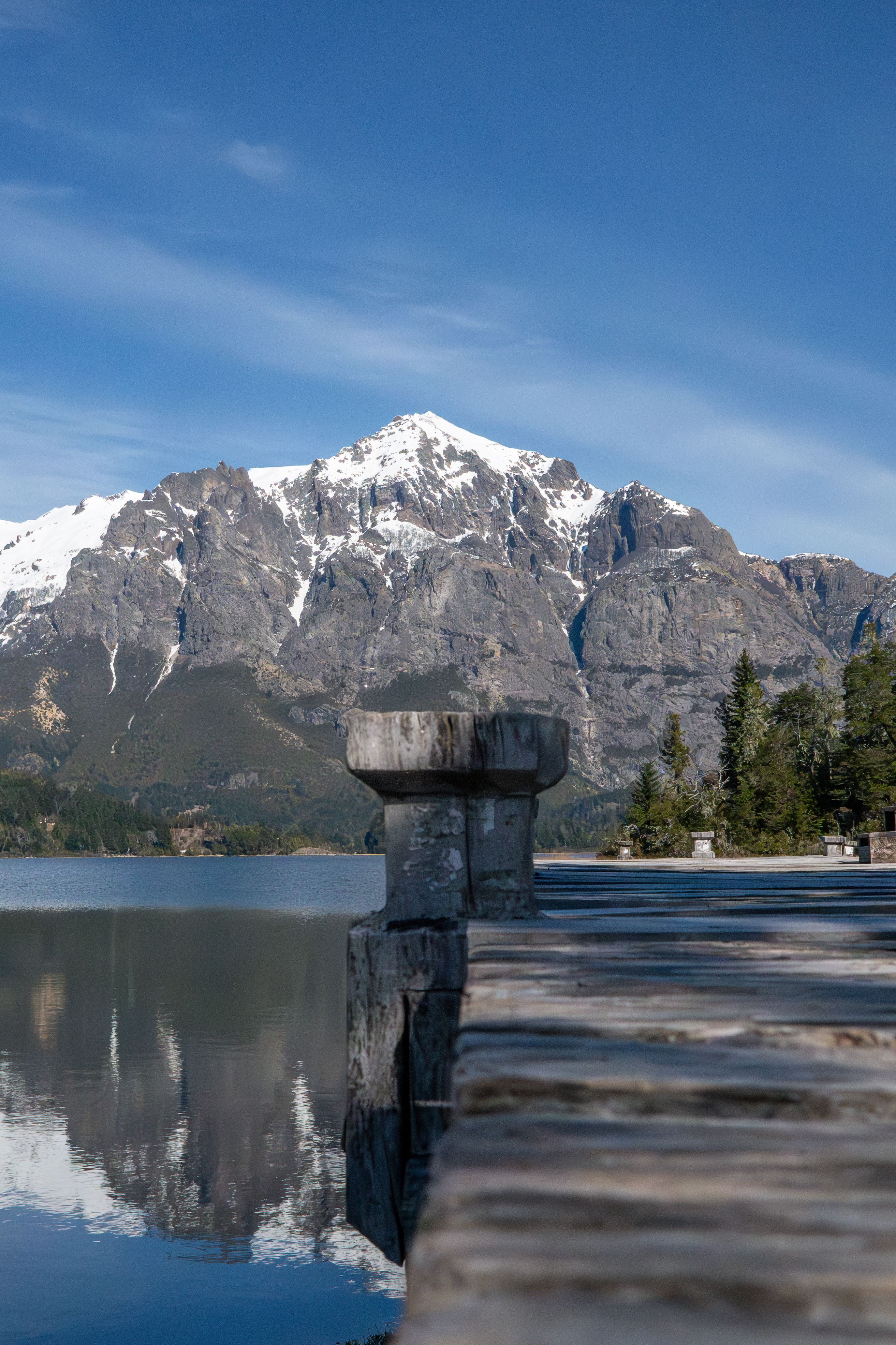 Breathtaking winter scene of a snowy mountain reflected in a tranquil lake in Bariloche, Argentina.
