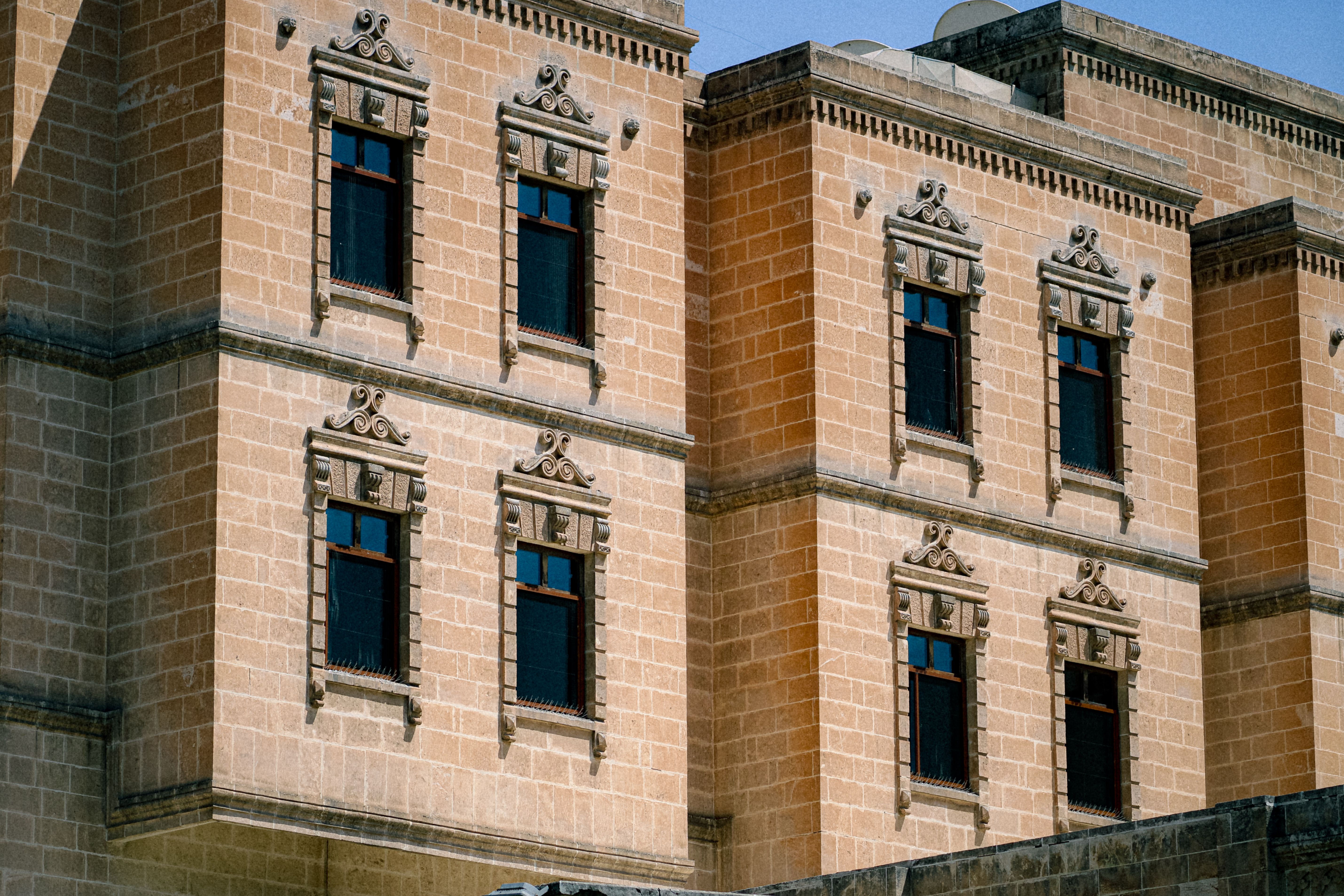 Close-up view of a historic stone facade featuring ornate window designs and gothic architecture.