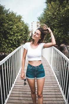 夏日里，一名女子闭着眼睛站在户外的木桥上