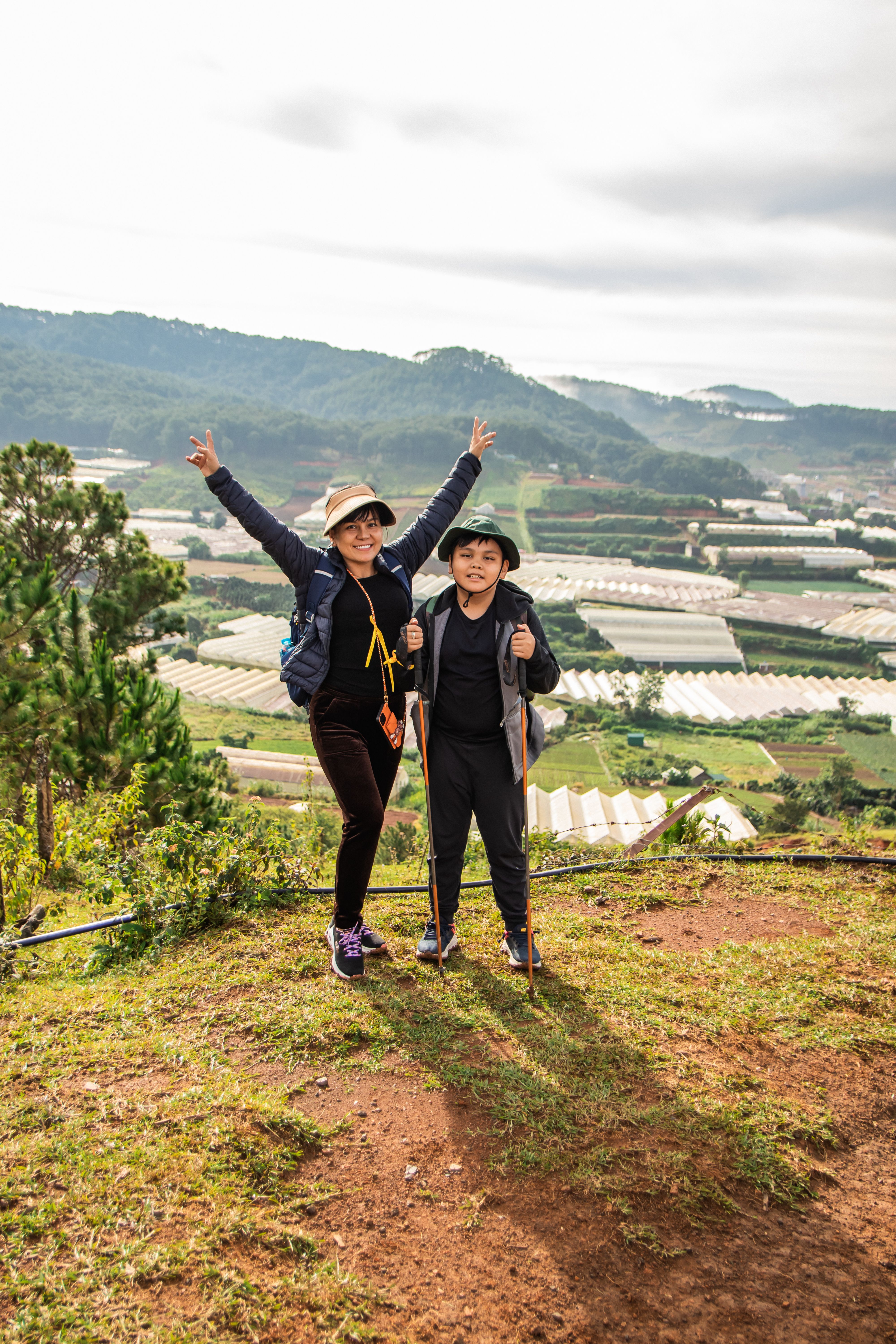 Two people standing on top of a hill with their arms up · Free Stock Photo