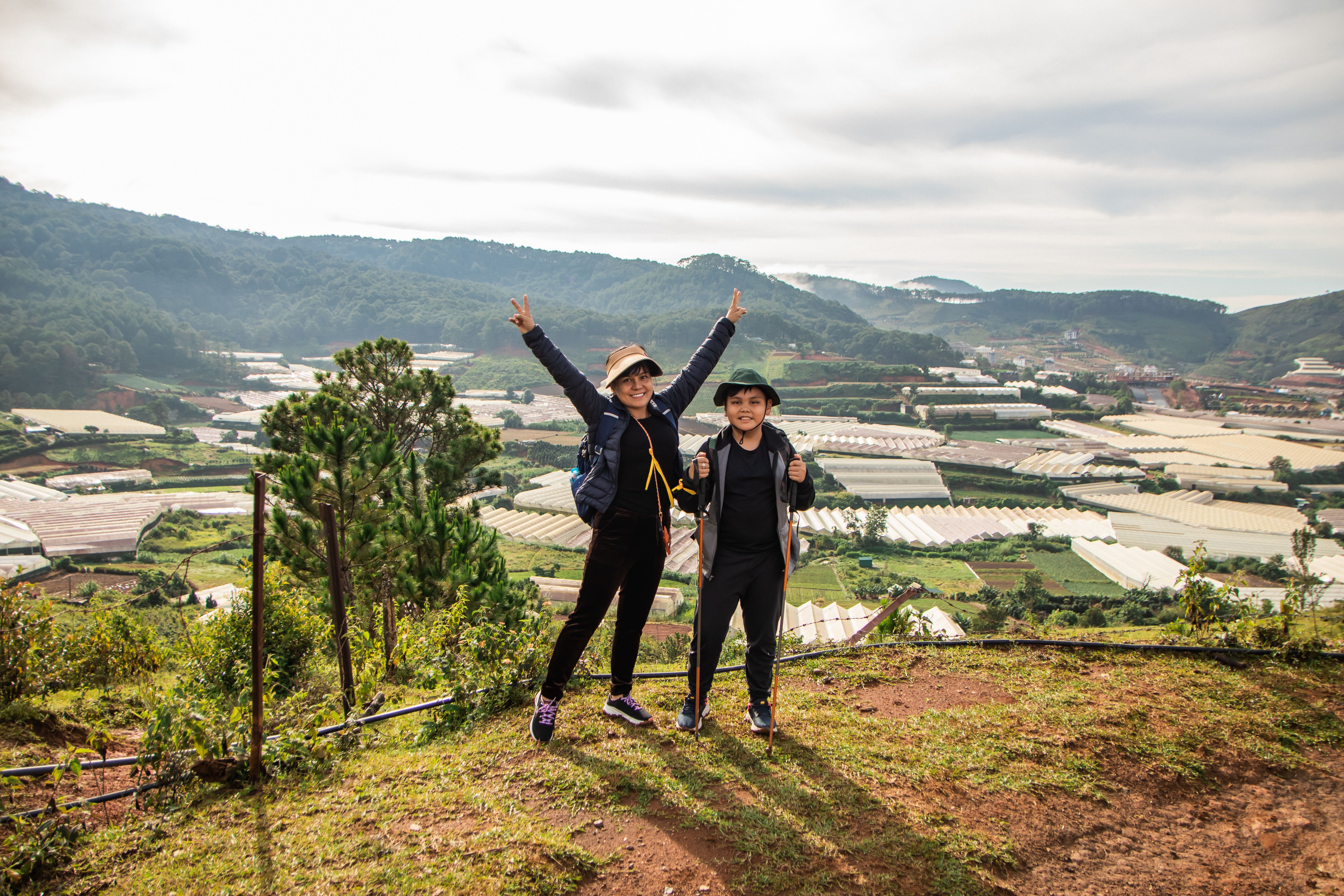 Two people standing on top of a hill with their arms up · Free Stock Photo