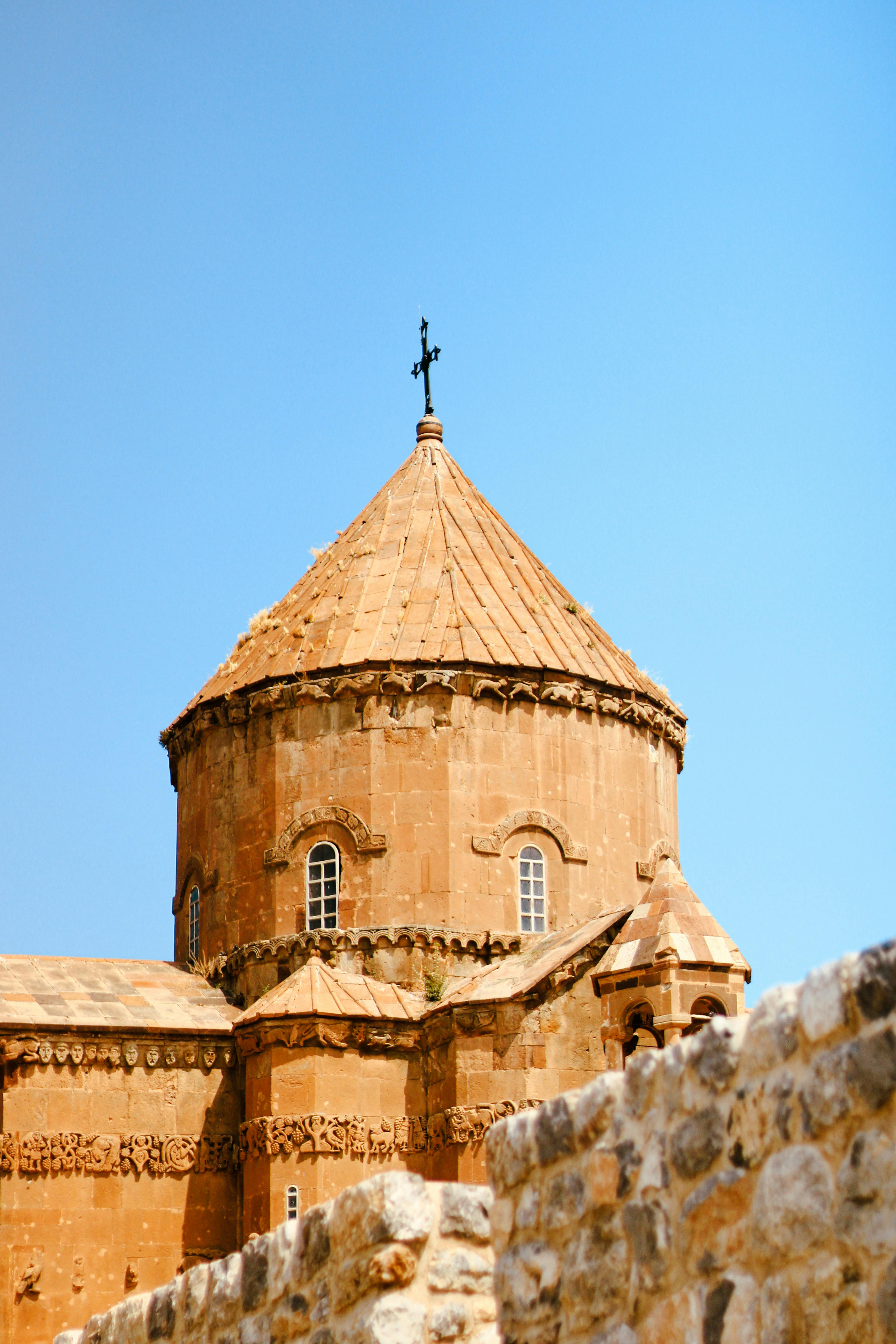 Beautiful view of an ancient Armenian church with distinctive architecture in Van, Türkiye, set against a blue sky.