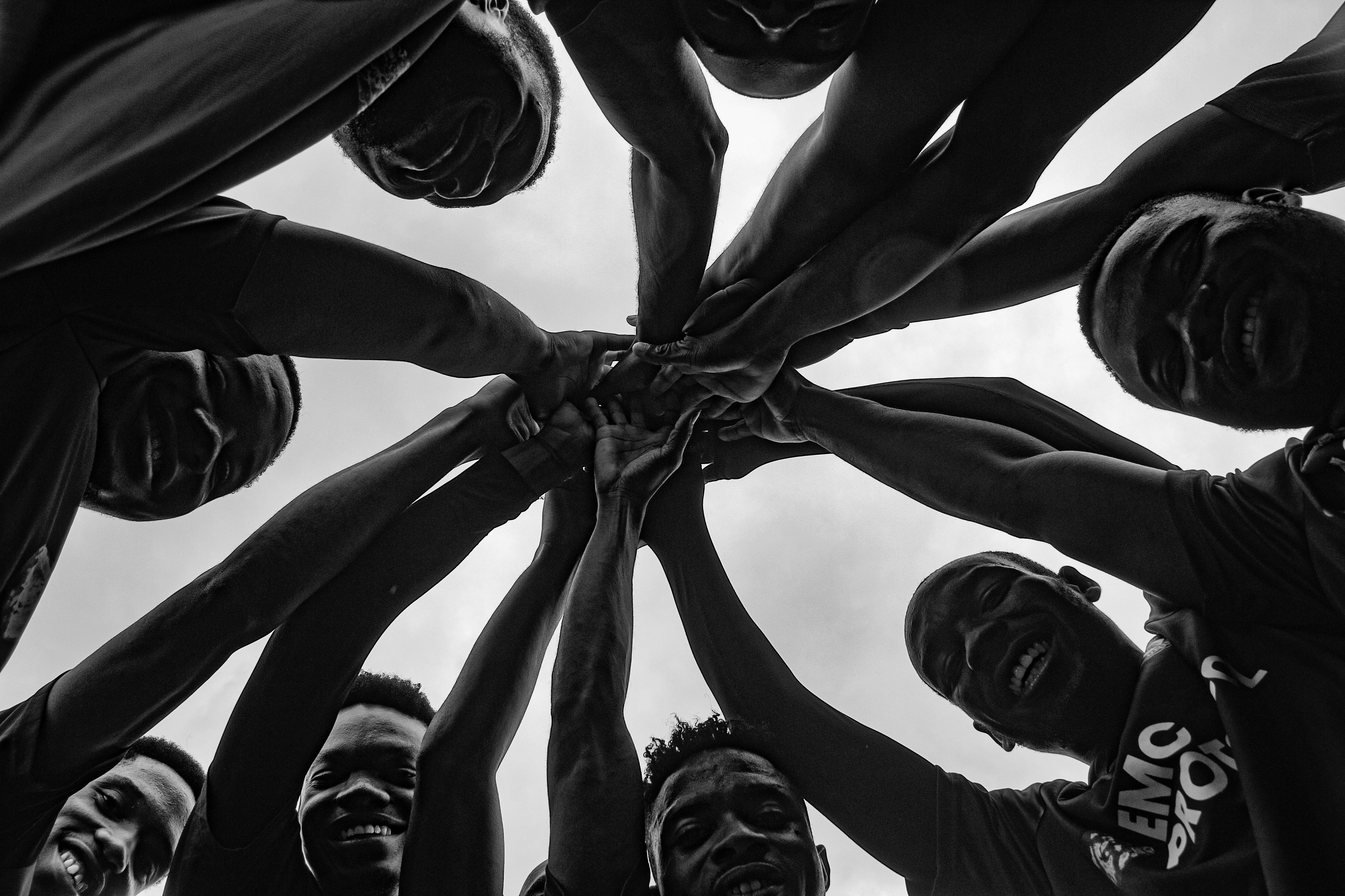 Silhouetted group of diverse adults holding hands in a circle, symbolizing unity and teamwork.