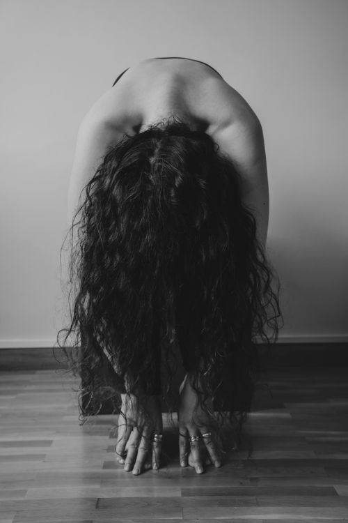 Free Elegant black and white photo of woman bending forward in yoga pose, highlighting beauty and grace. Stock Photo