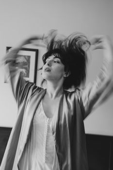 A captivating black and white portrait of a woman with expressive movement indoors.