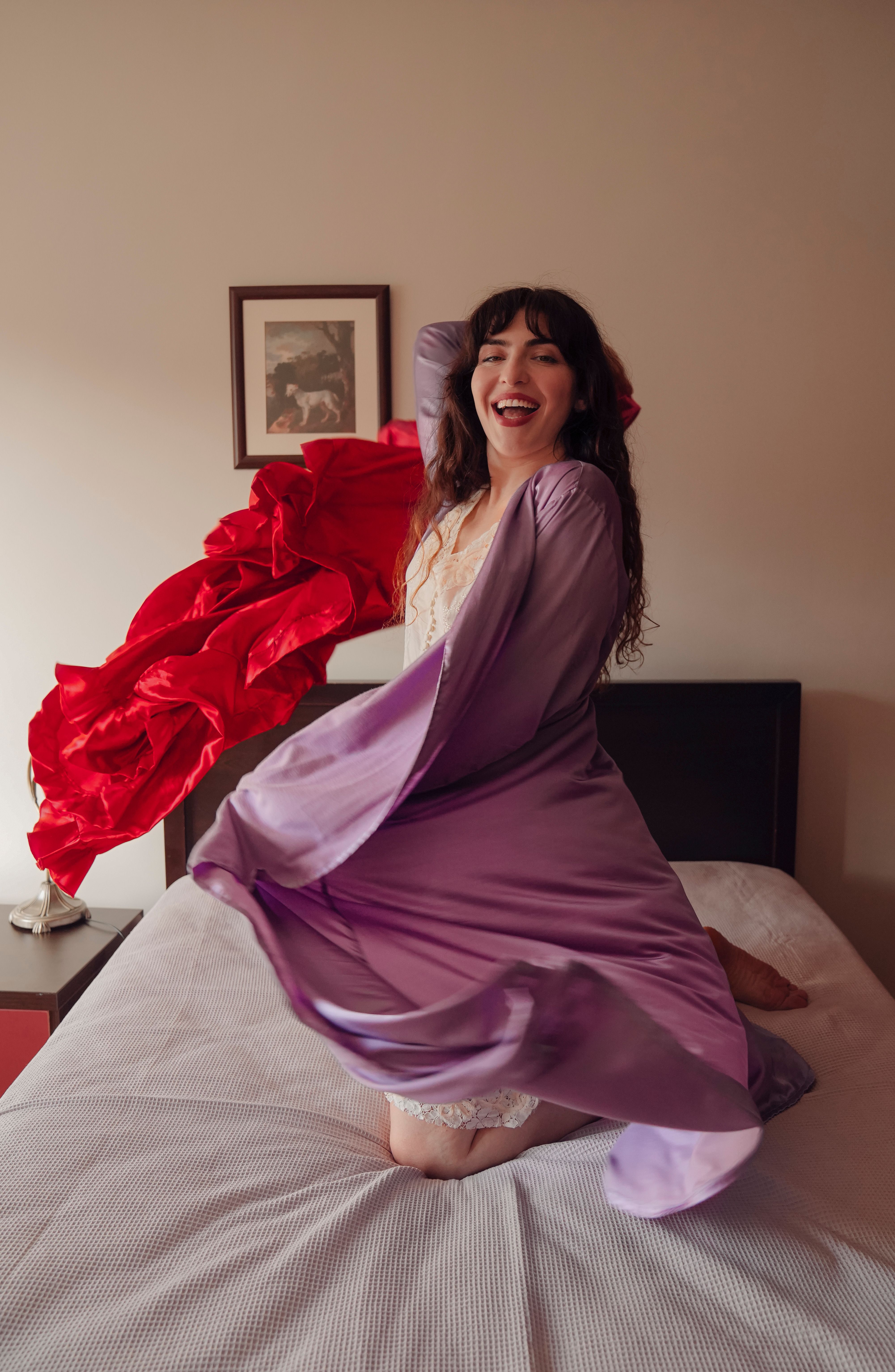 A woman in a purple robe is dancing on a bed · Free Stock Photo