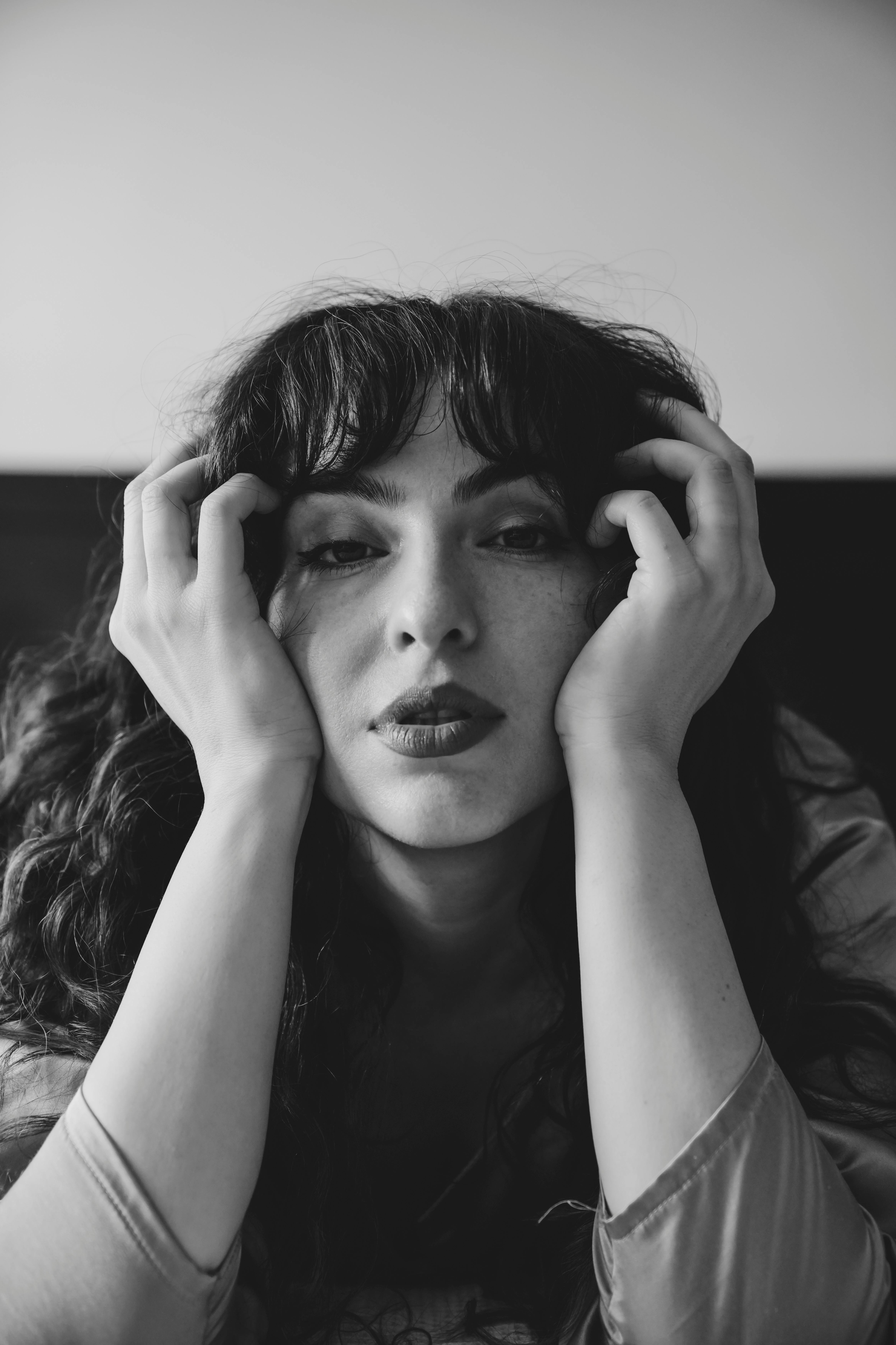 Artistic black and white portrait of a young woman with curly hair, conveying deep emotions.