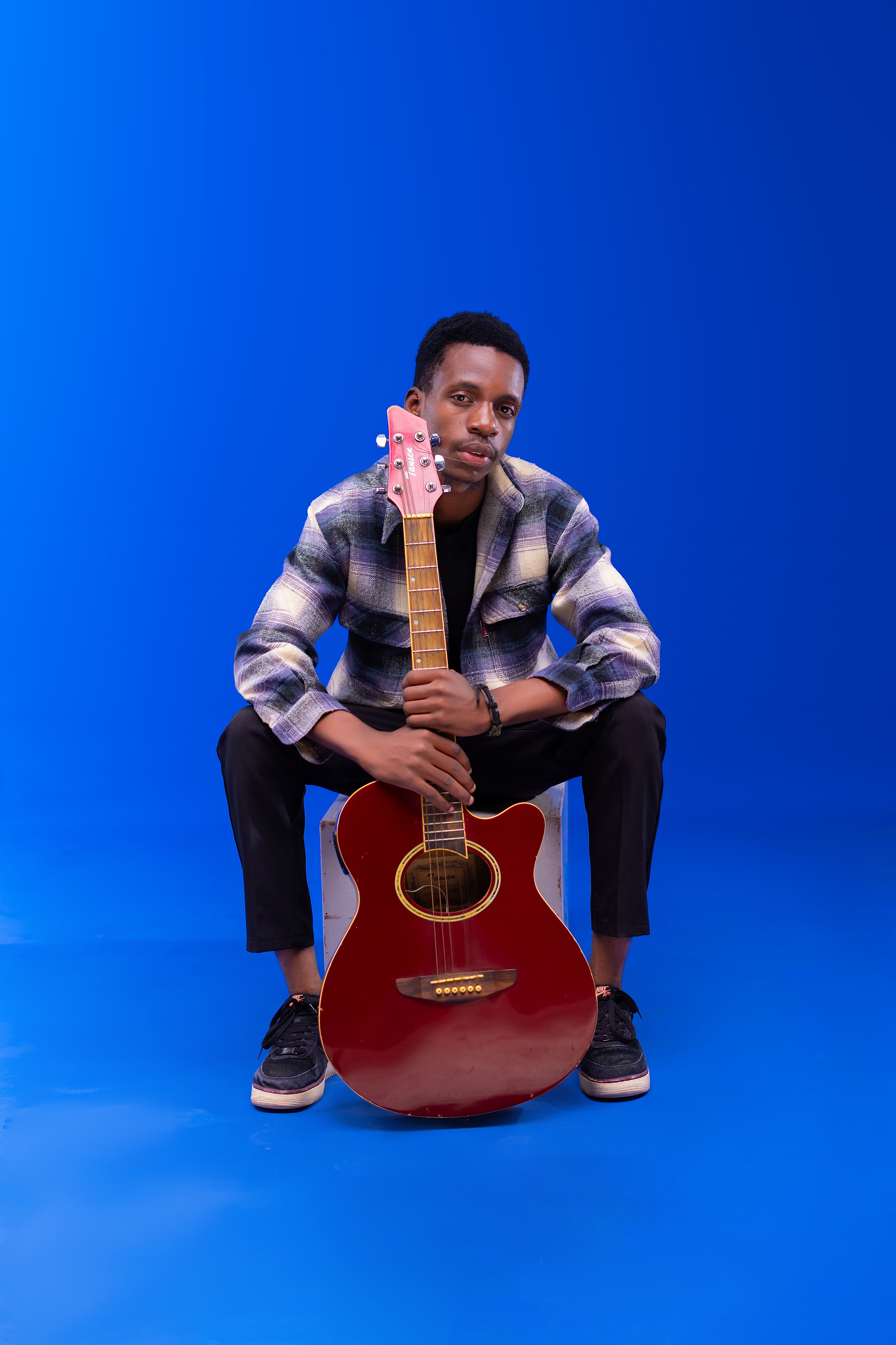 A young man sitting on a chair with a guitar · Free Stock Photo