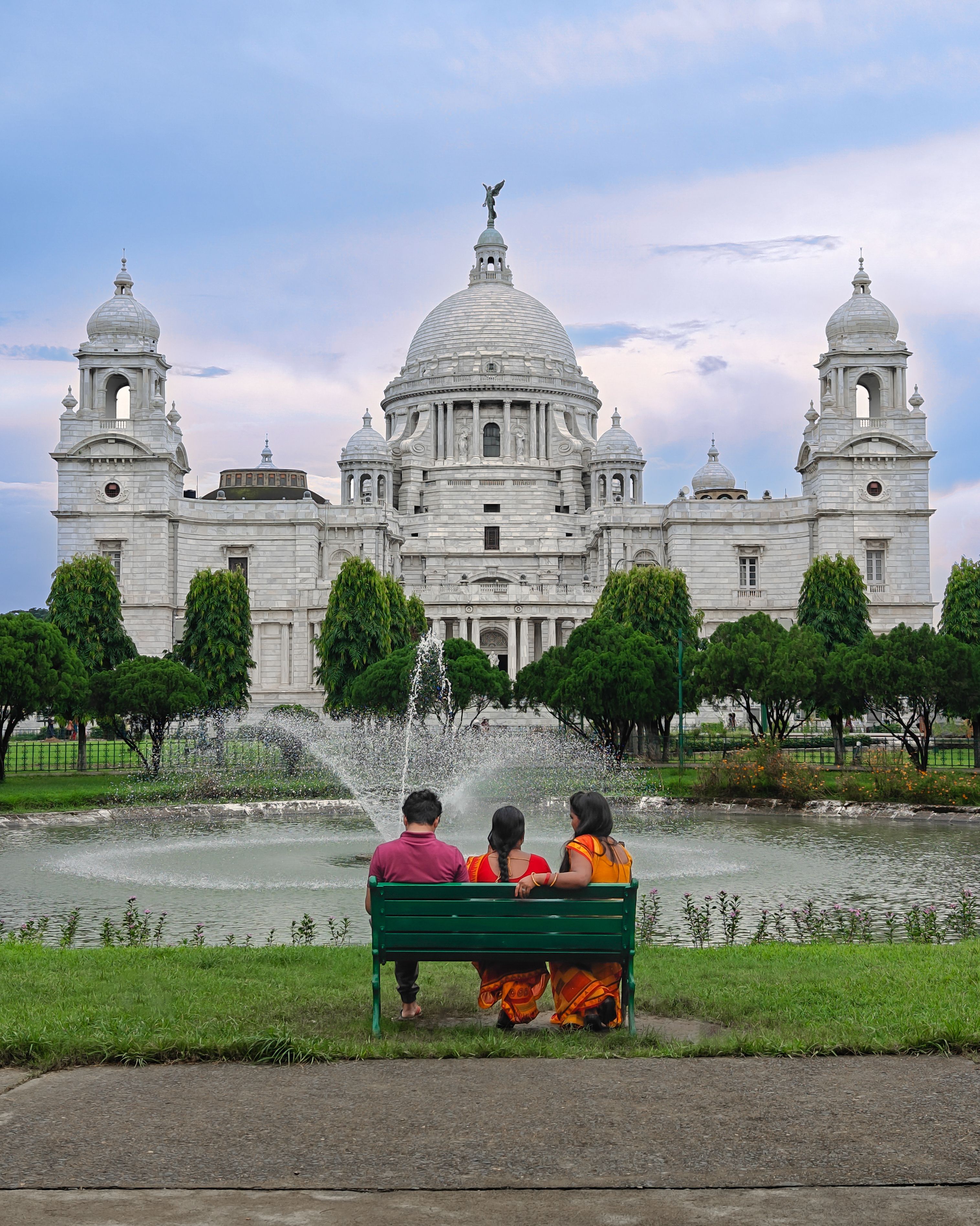 Two people sitting on a bench in front of a large building · Free Stock ...