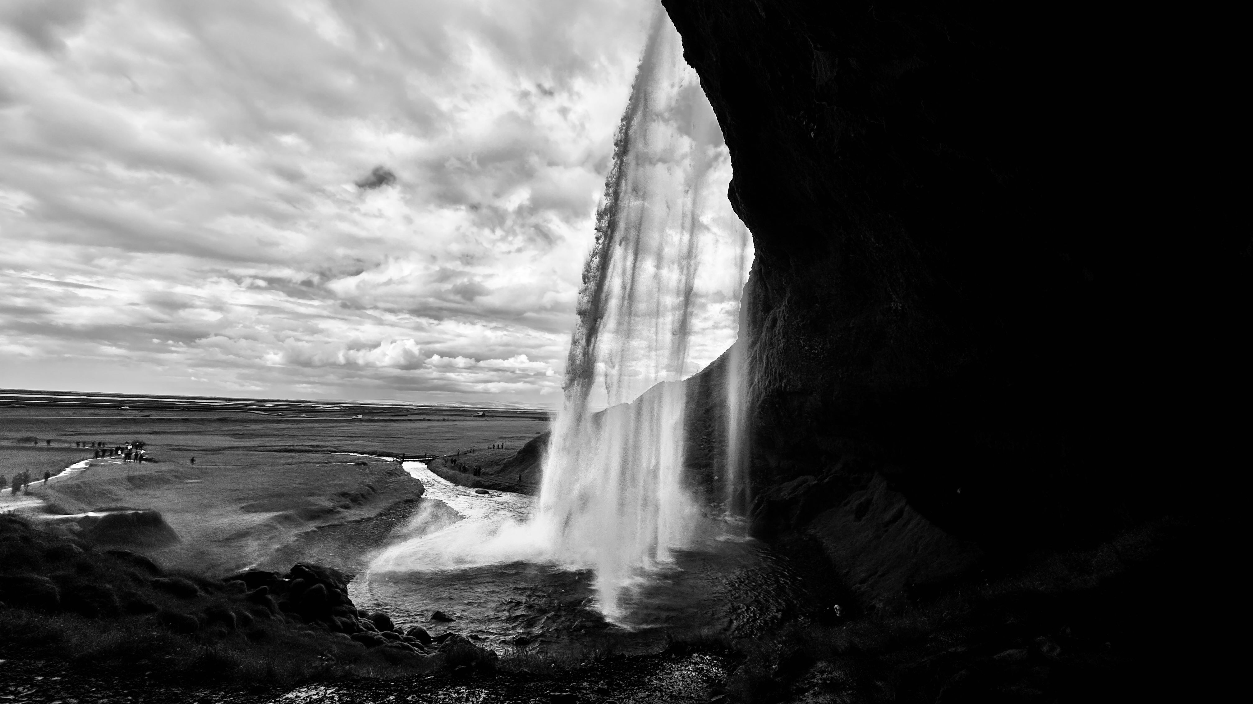 Tourists walking behind Seljalandsfoss waterfall in Iceland