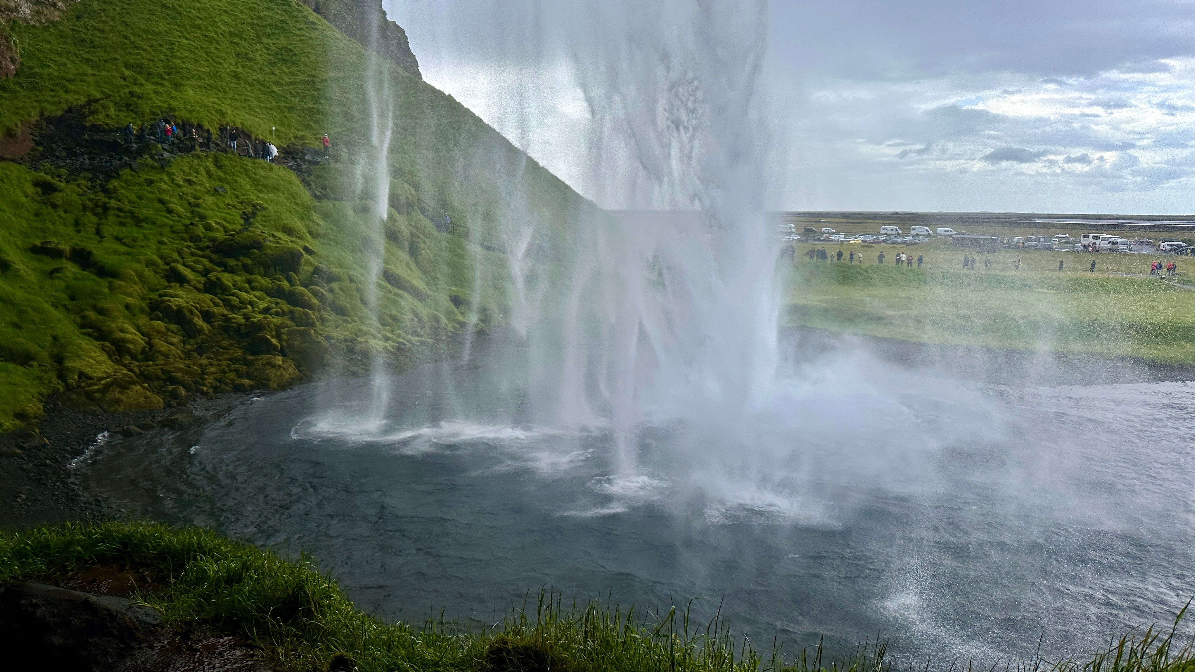 A large waterfall is in the middle of a green field · Free Stock Photo
