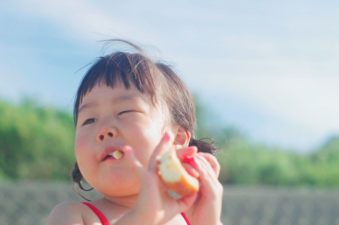 A small child eating a piece of soft fruit