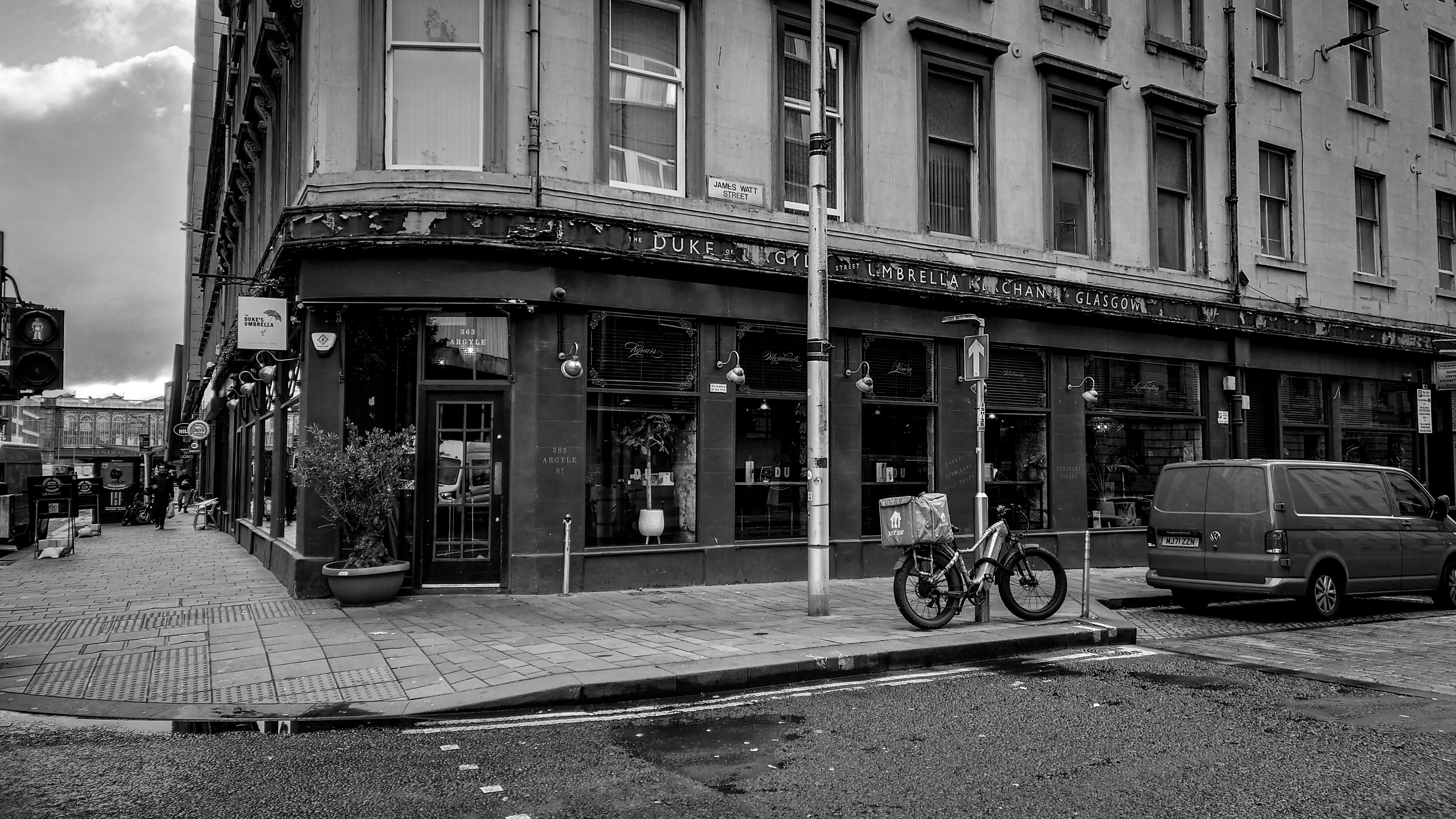 a black and white photo of a bike parked in front of a building