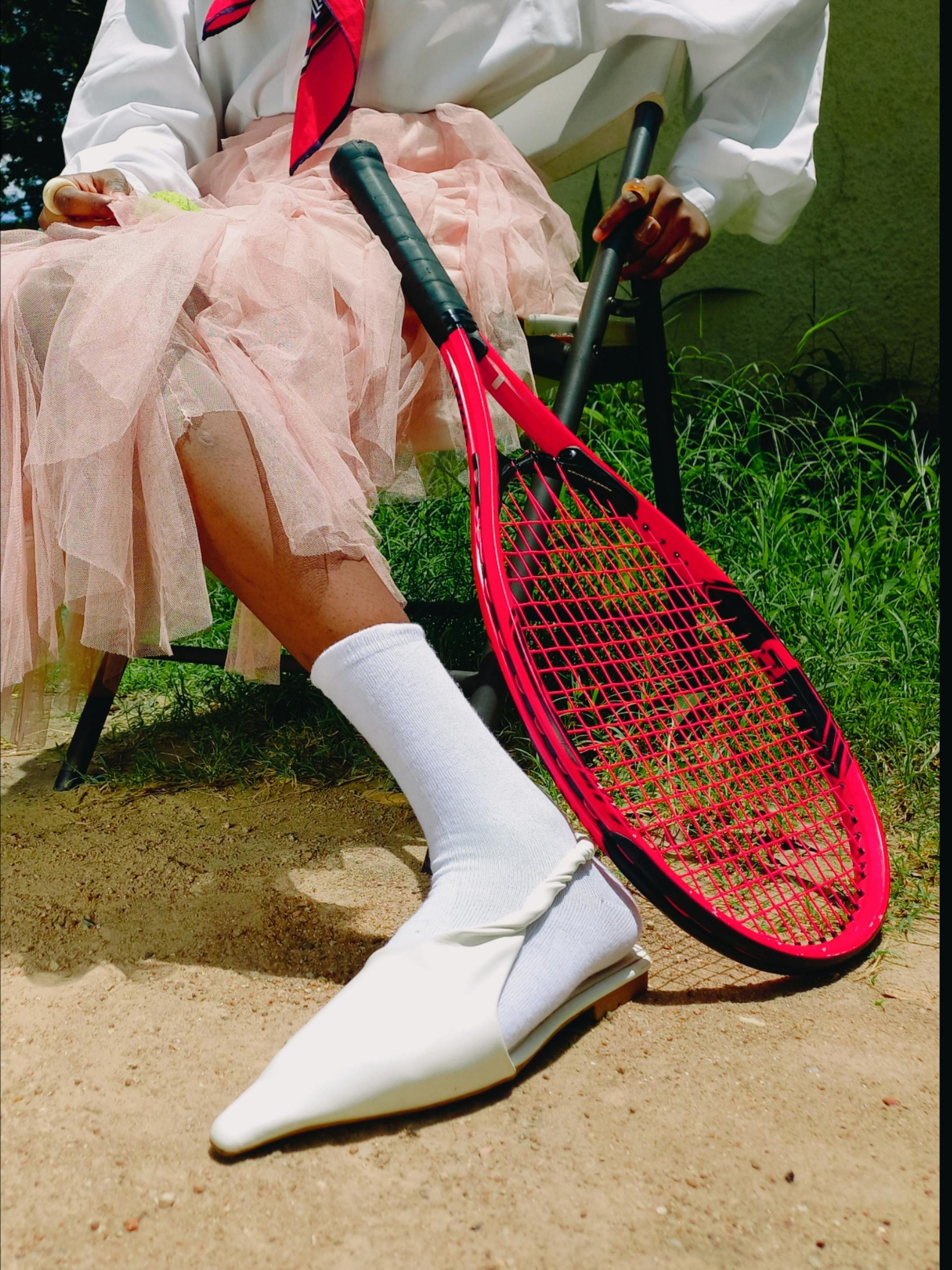 Stylish attire combines tennis gear with a chic pink tulle skirt, capturing a unique blend of sport and fashion.