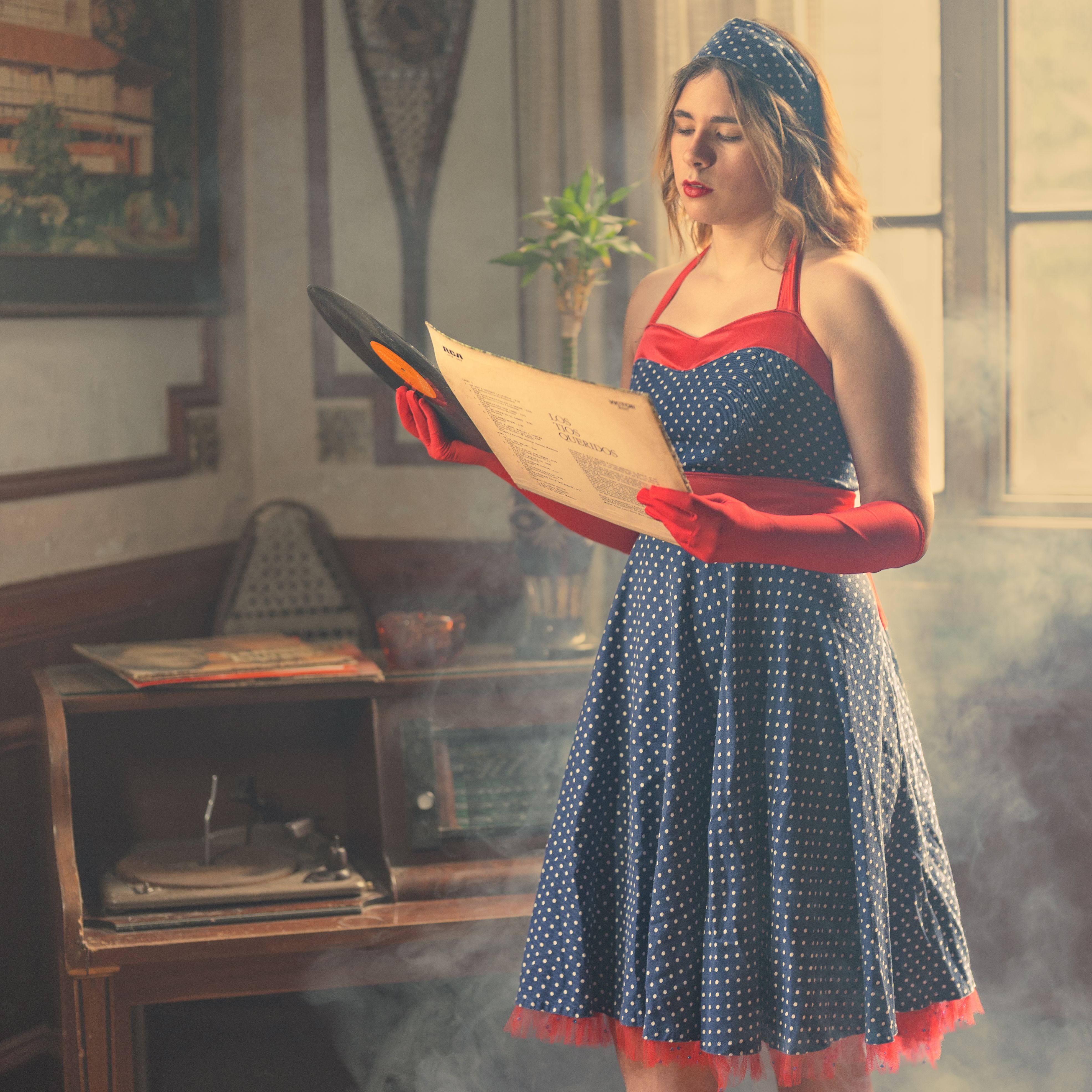 A woman in a blue and white dress is holding a record