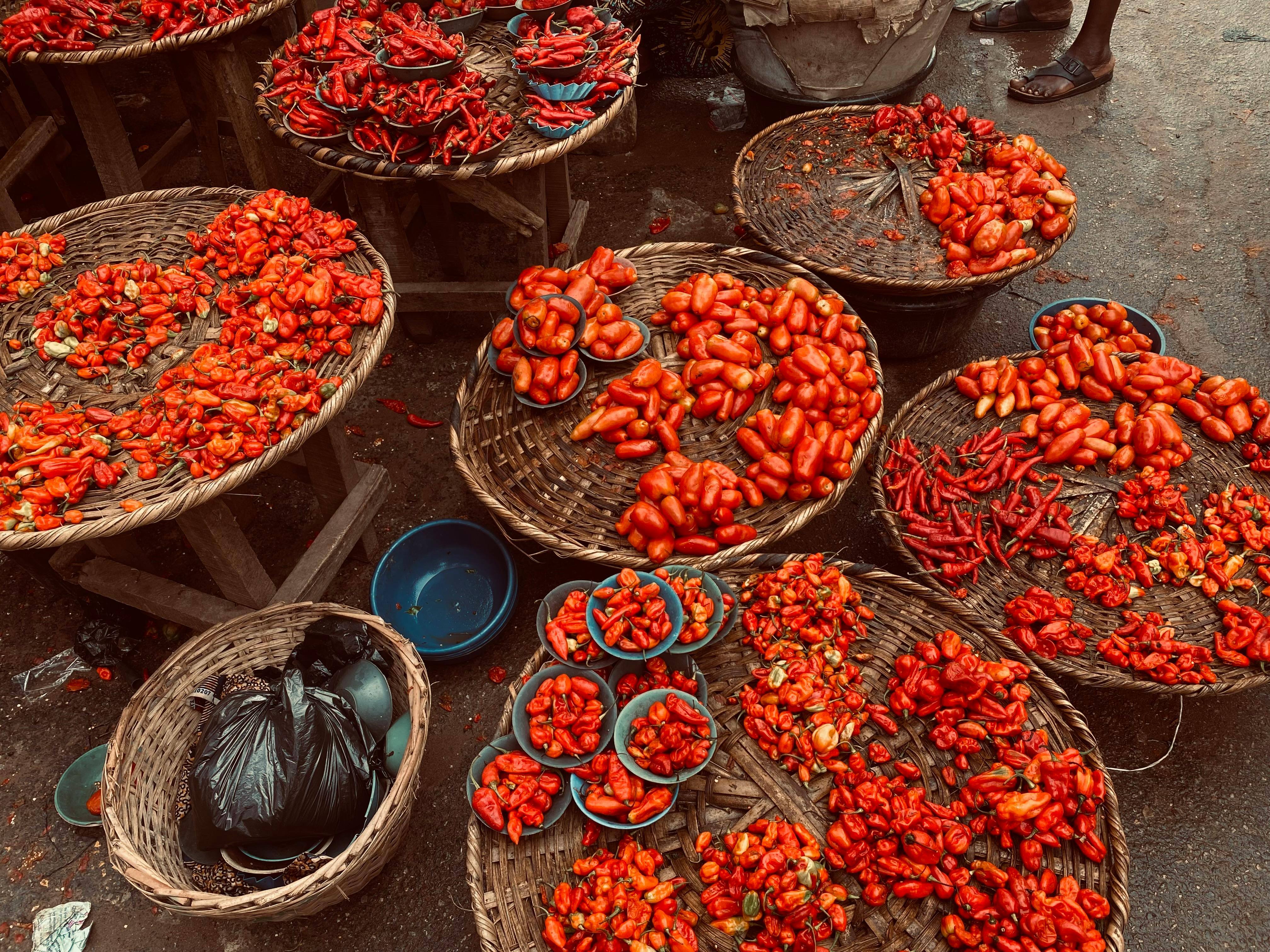 a market with baskets of tomatoes and other vegetables