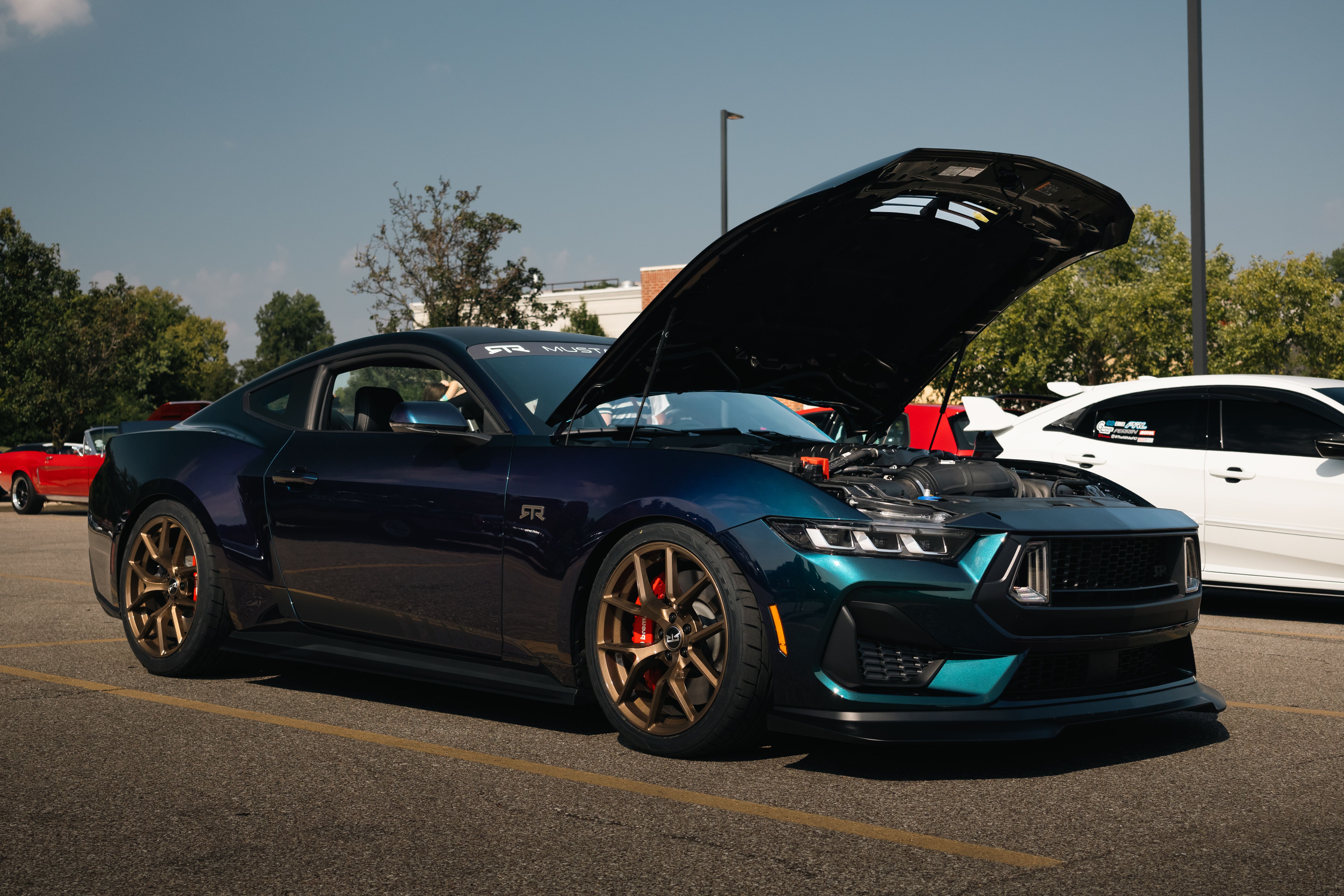 A stunning high-performance car with its hood open at an outdoor car show.