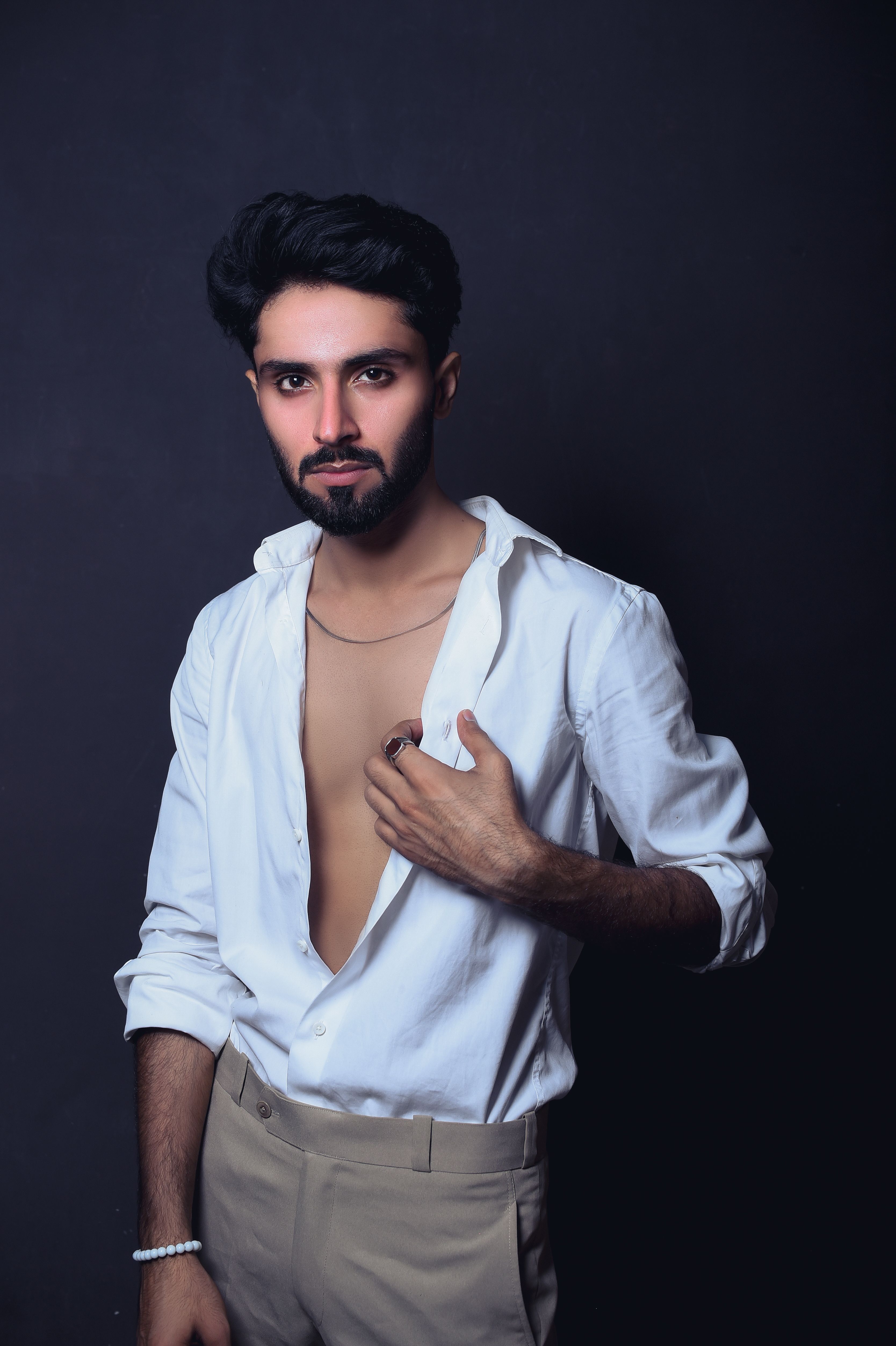 Portrait of a stylish young man in a white shirt with a dark backdrop.
