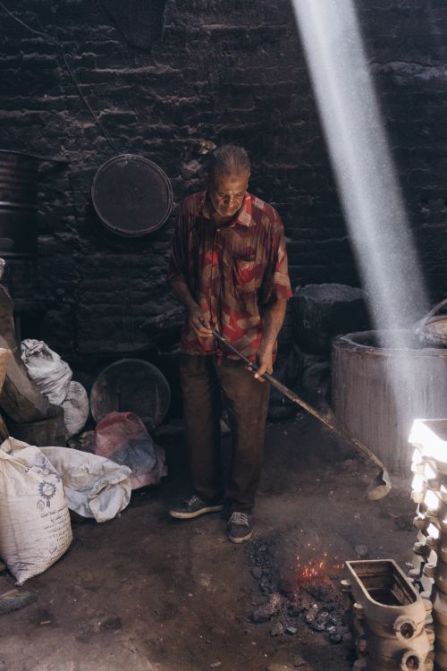 Free An elderly man works in a dimly lit blacksmith workshop in Alexandria, Egypt. Stock Photo