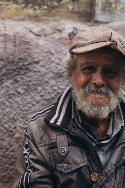 Free A warm portrait of an elderly man with a beard and cap, sitting outdoors in Alexandria, Egypt. Stock Photo