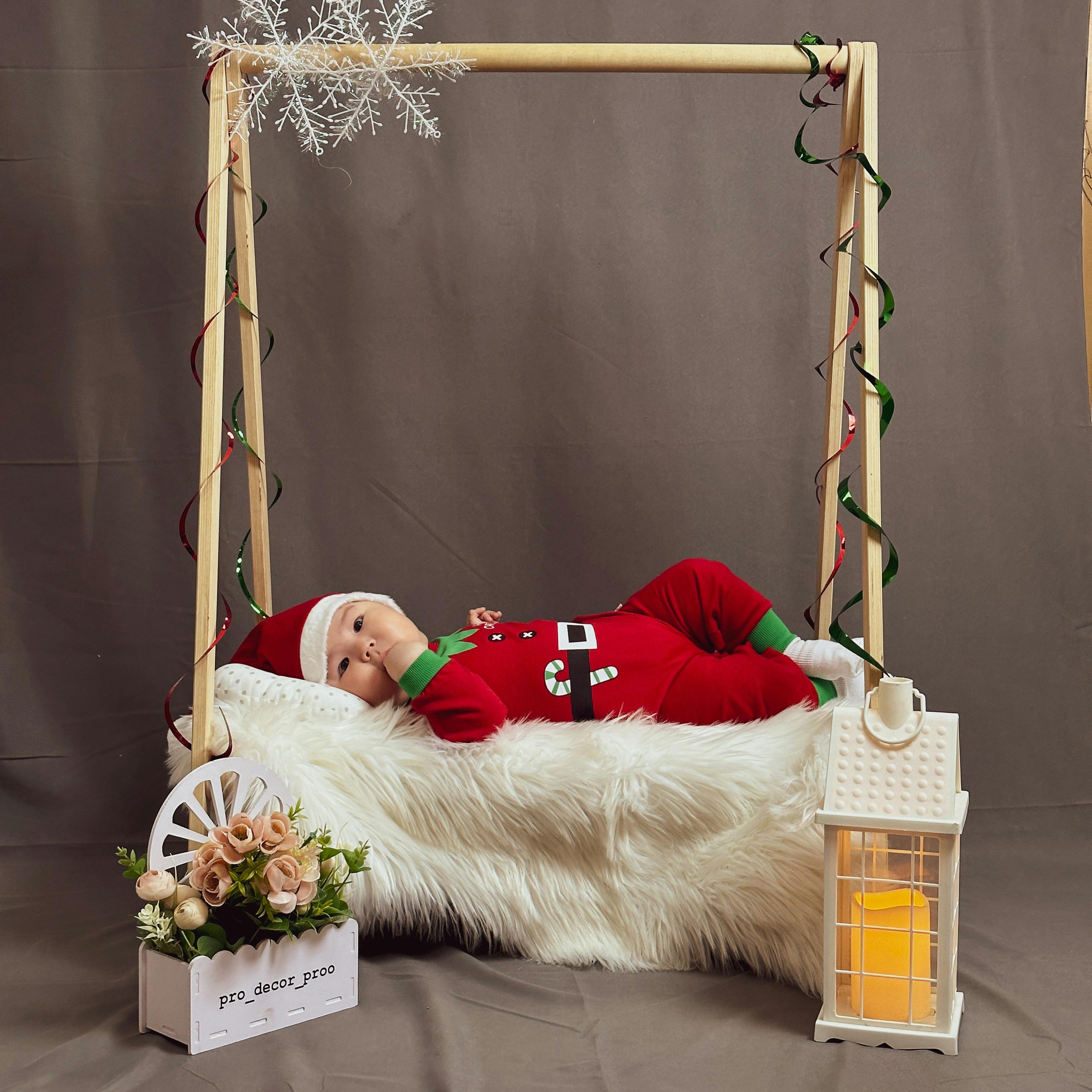 A baby in a santa outfit is laying in a swing