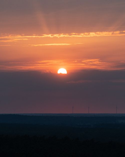 Free Stunning sunset view with glowing sun setting over the forests of Reken, Germany. Stock Photo