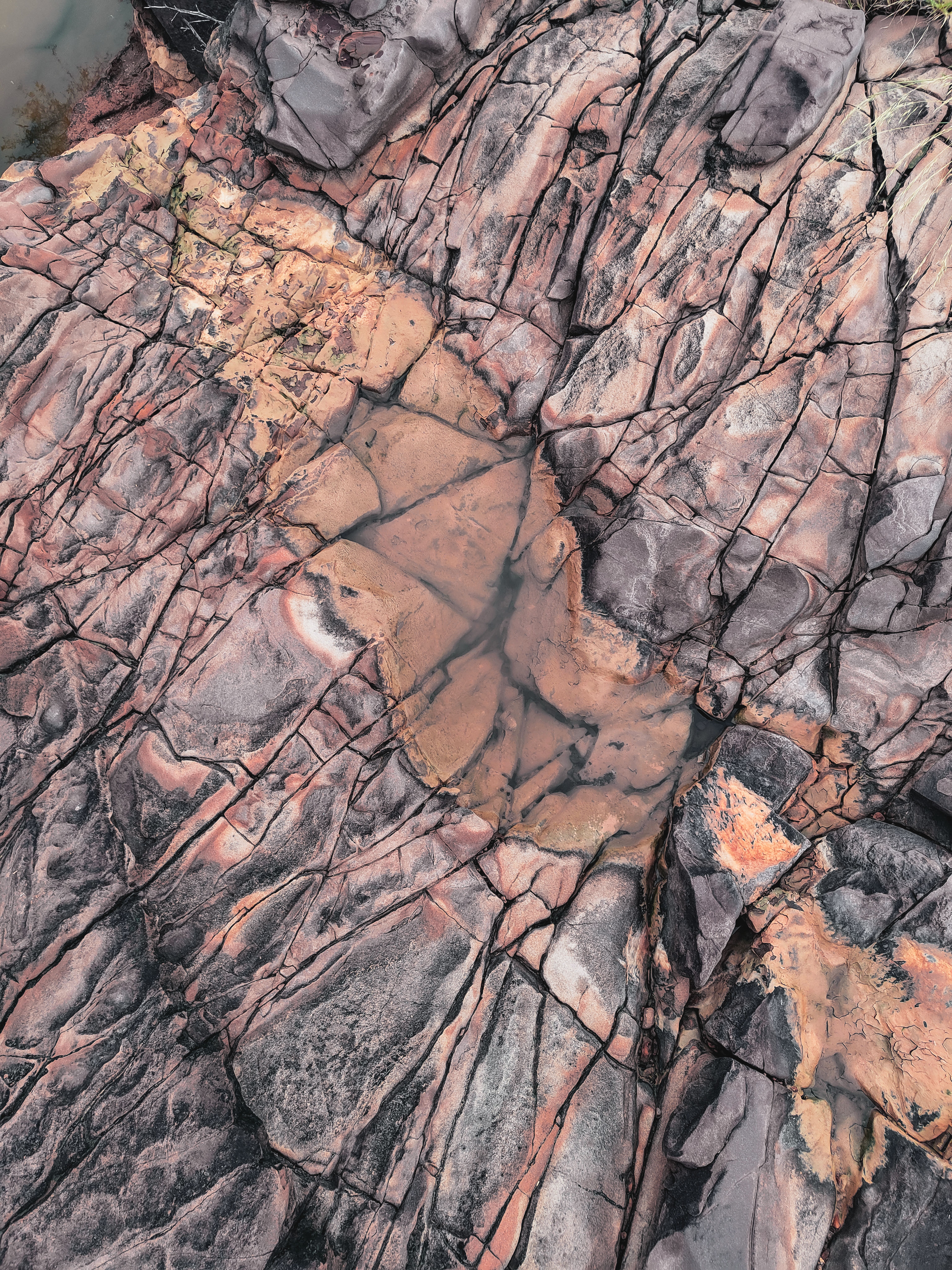 Aerial view of a weathered geological rock formation with intricate natural cracks and earthy tones.