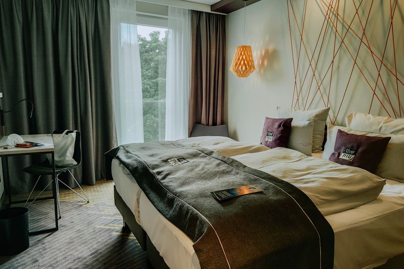 A modern and cozy hotel room featuring a double bed, stylish lighting, and a workspace.
